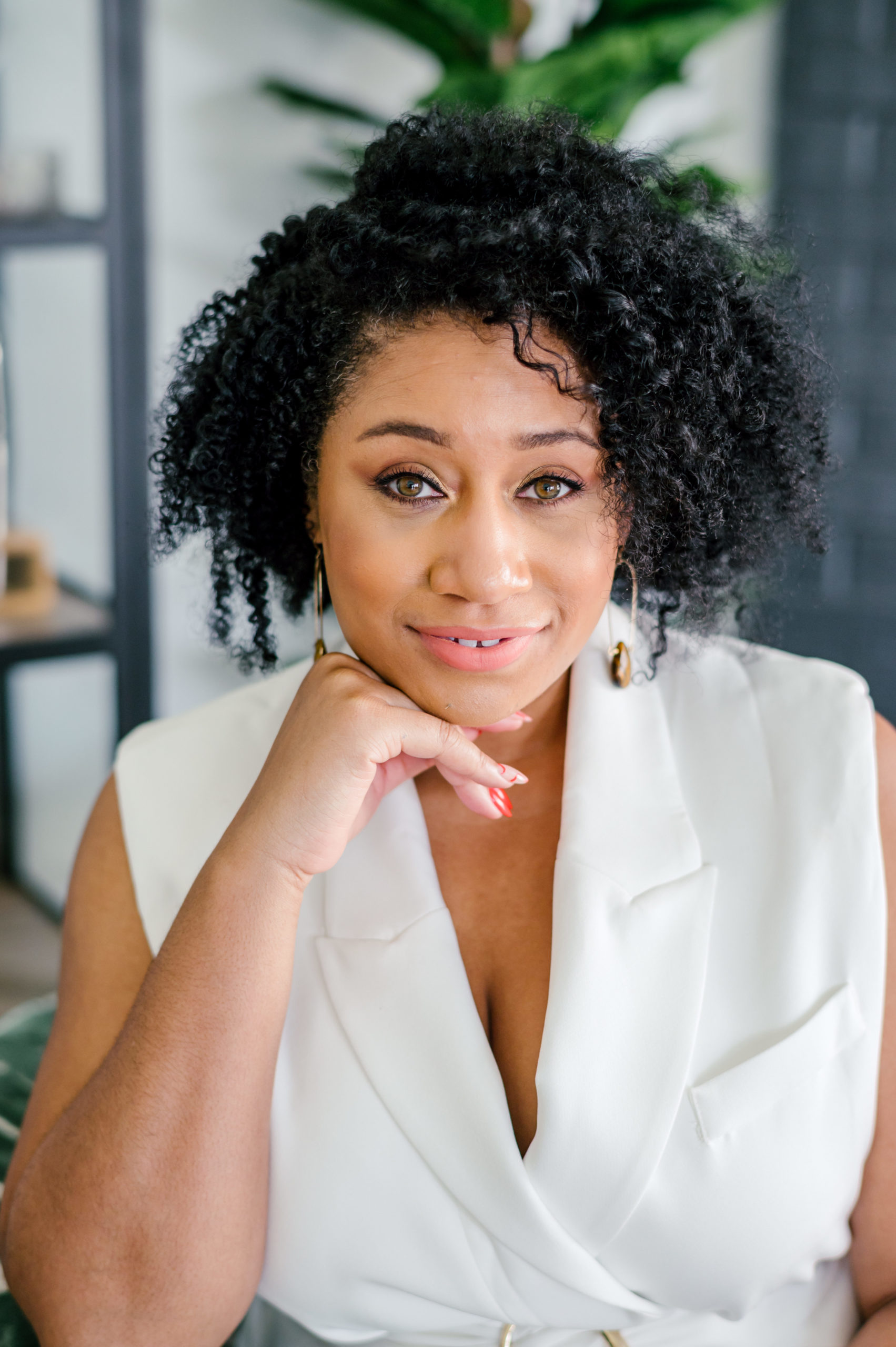 Interior designer wearing a white blouse while leaning her head on her hand smiling