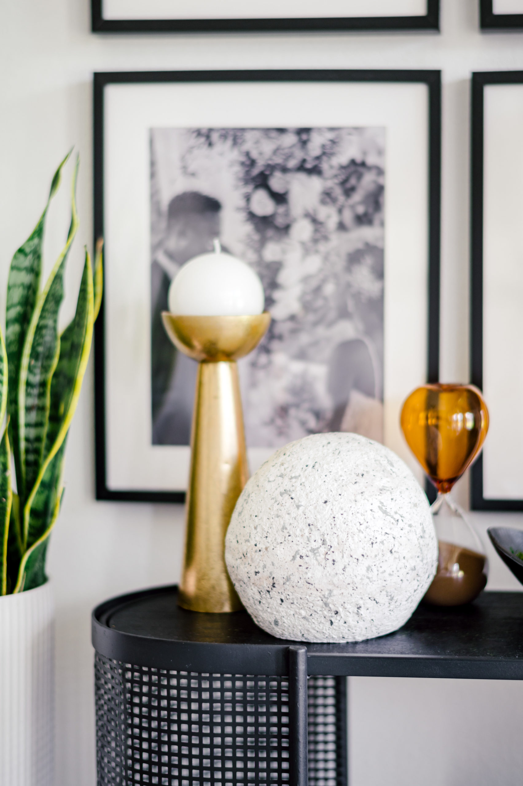 White and gold candle standing next to a decorative rock on top of a black table