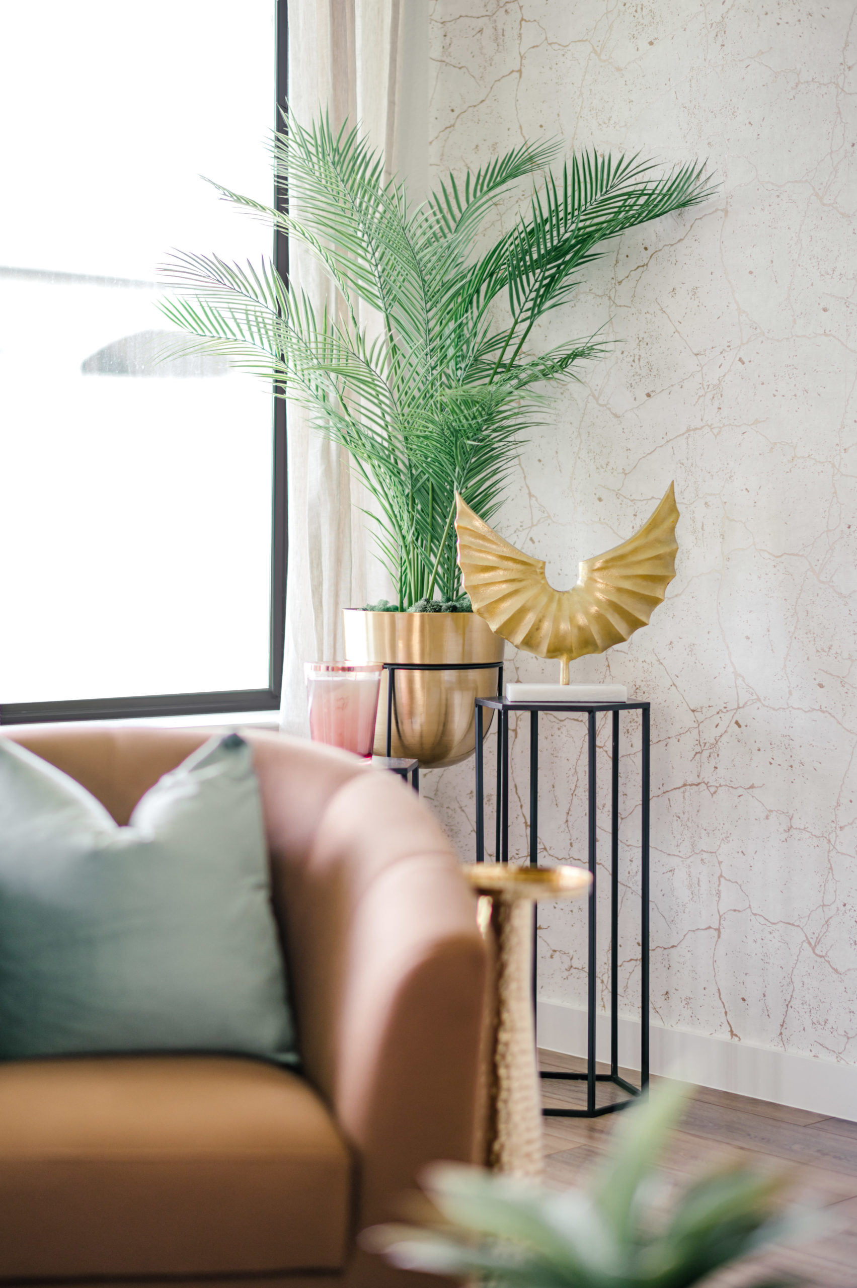 Brown leather loveseat with a light green pillow sitting next to a plant and decor