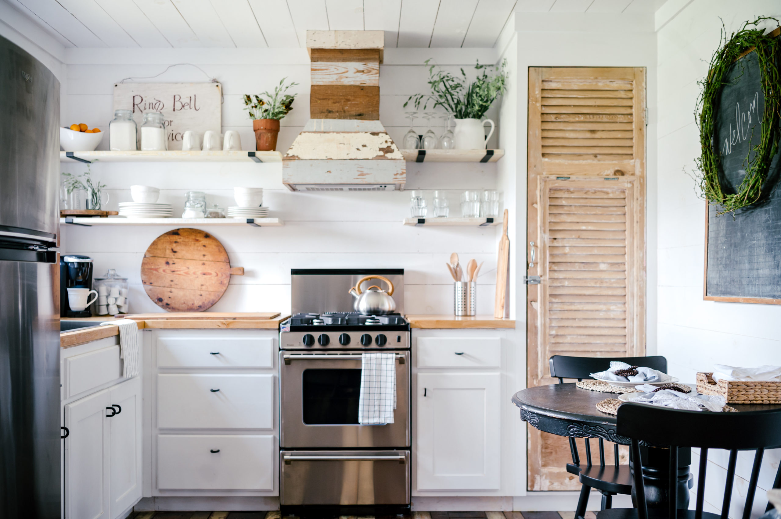 Airbnb photography of kitchen with white cabinets, wooden tabletops, stainless steel stovetop and over