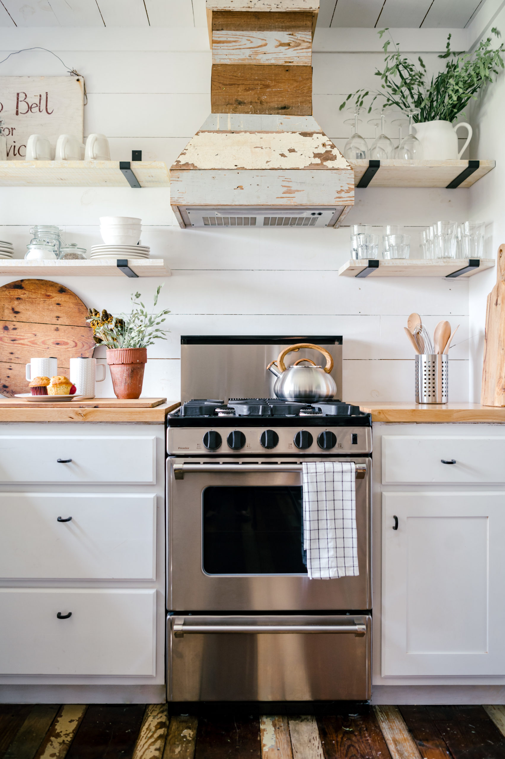 Airbnb photography of kitchen with white cabinets, wooden tabletops, stainless steel stovetop and over