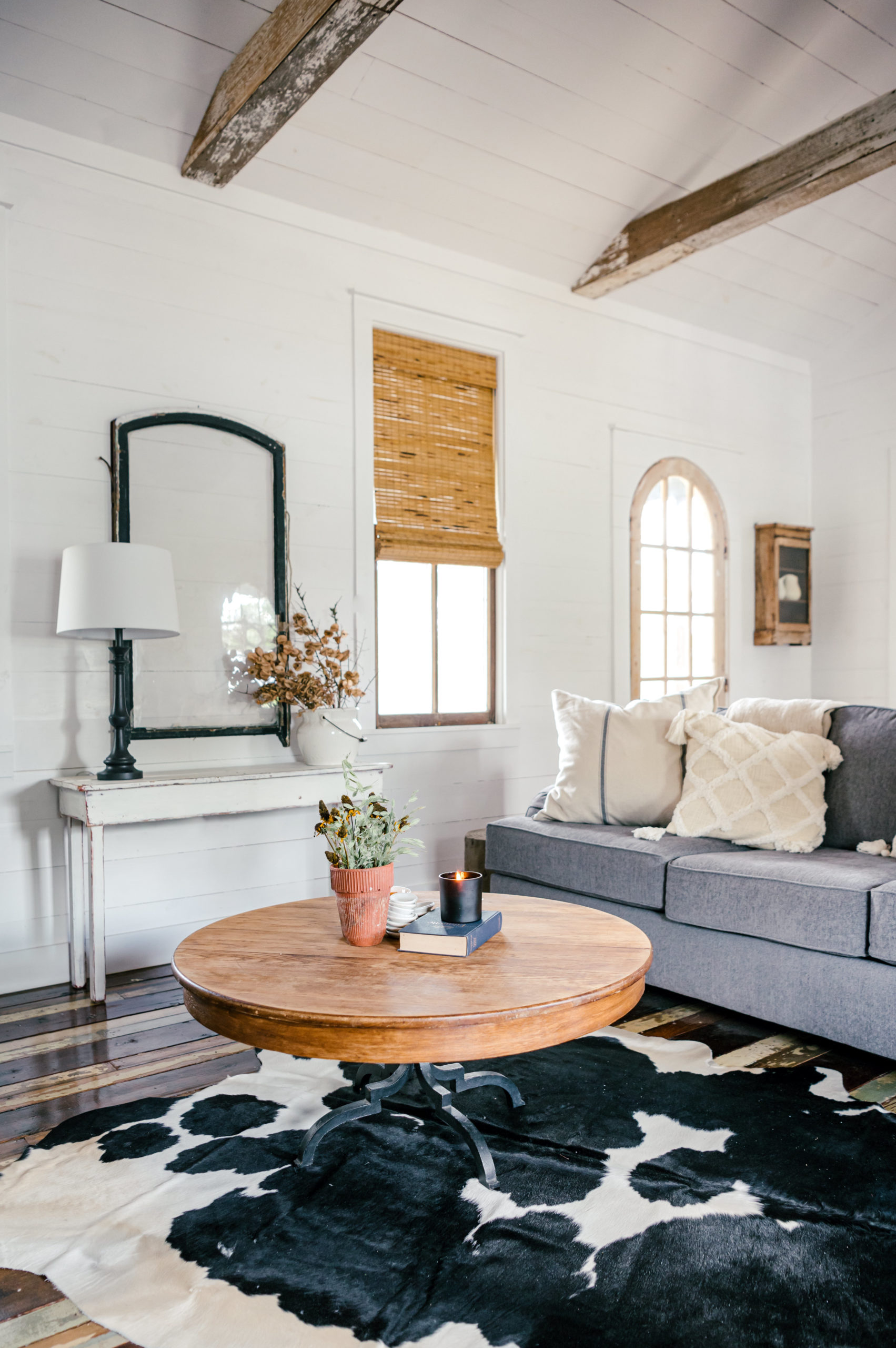 Airbnb Photography of living room with cow skin rug, grey couch, and checkered love seat