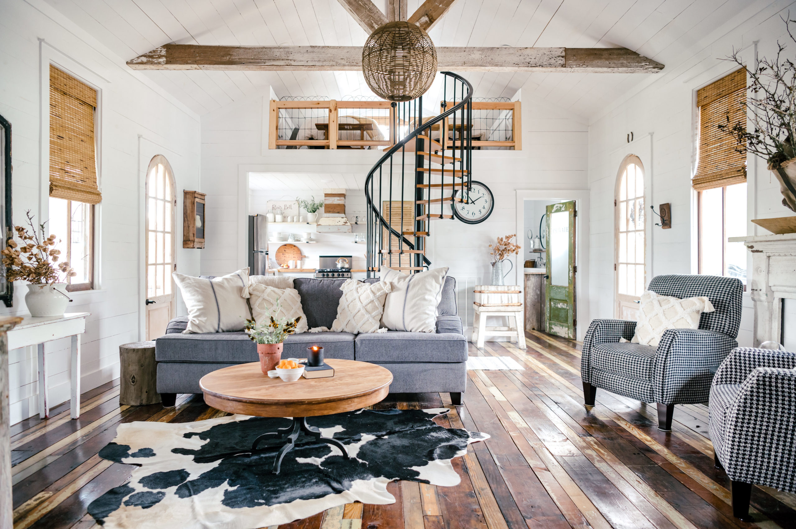 Airbnb Photography of living room with cow skin rug, grey couch, and checkered love seat