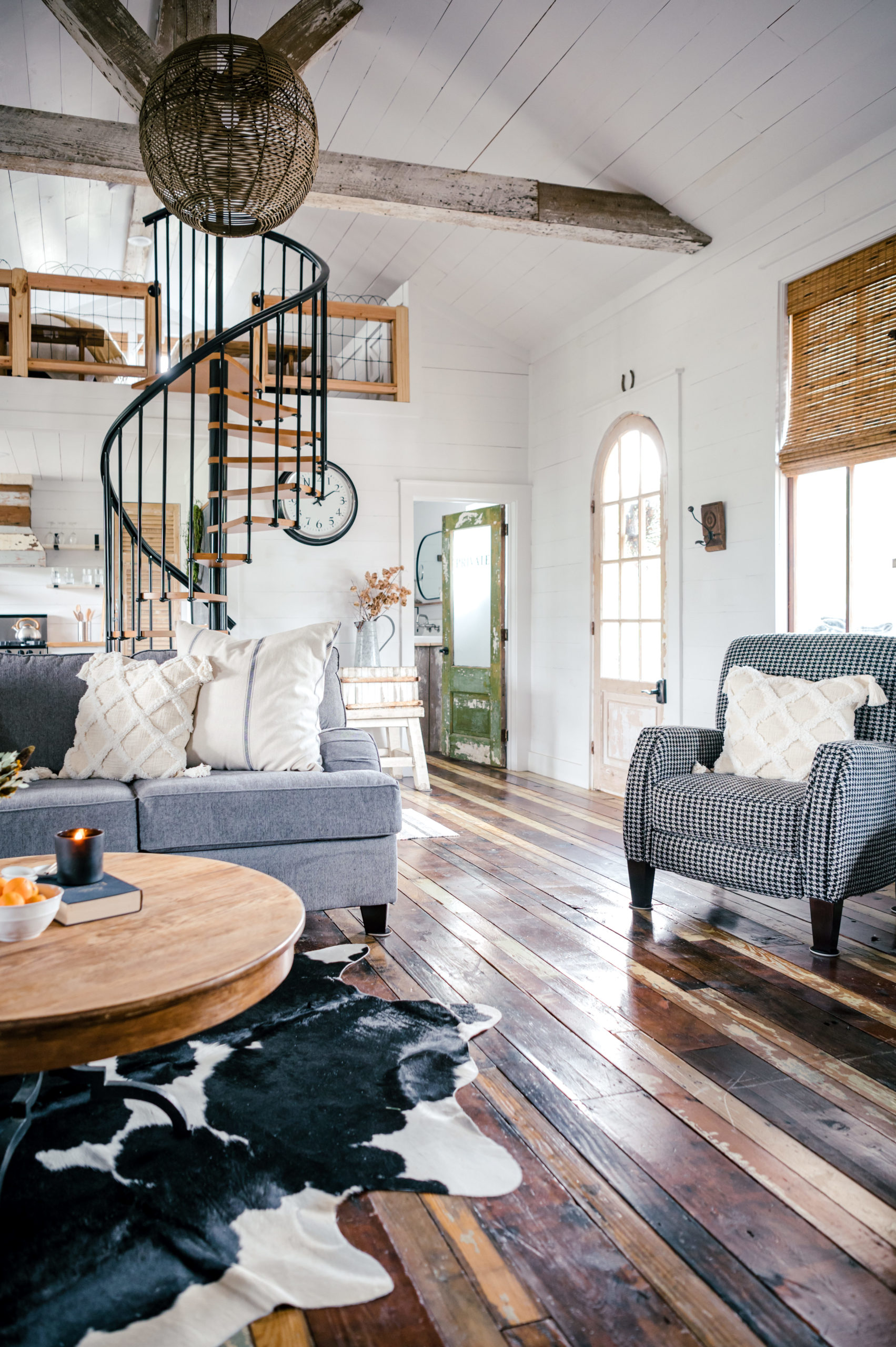 Airbnb Photography of living room with cow skin rug, grey couch, and checkered love seat