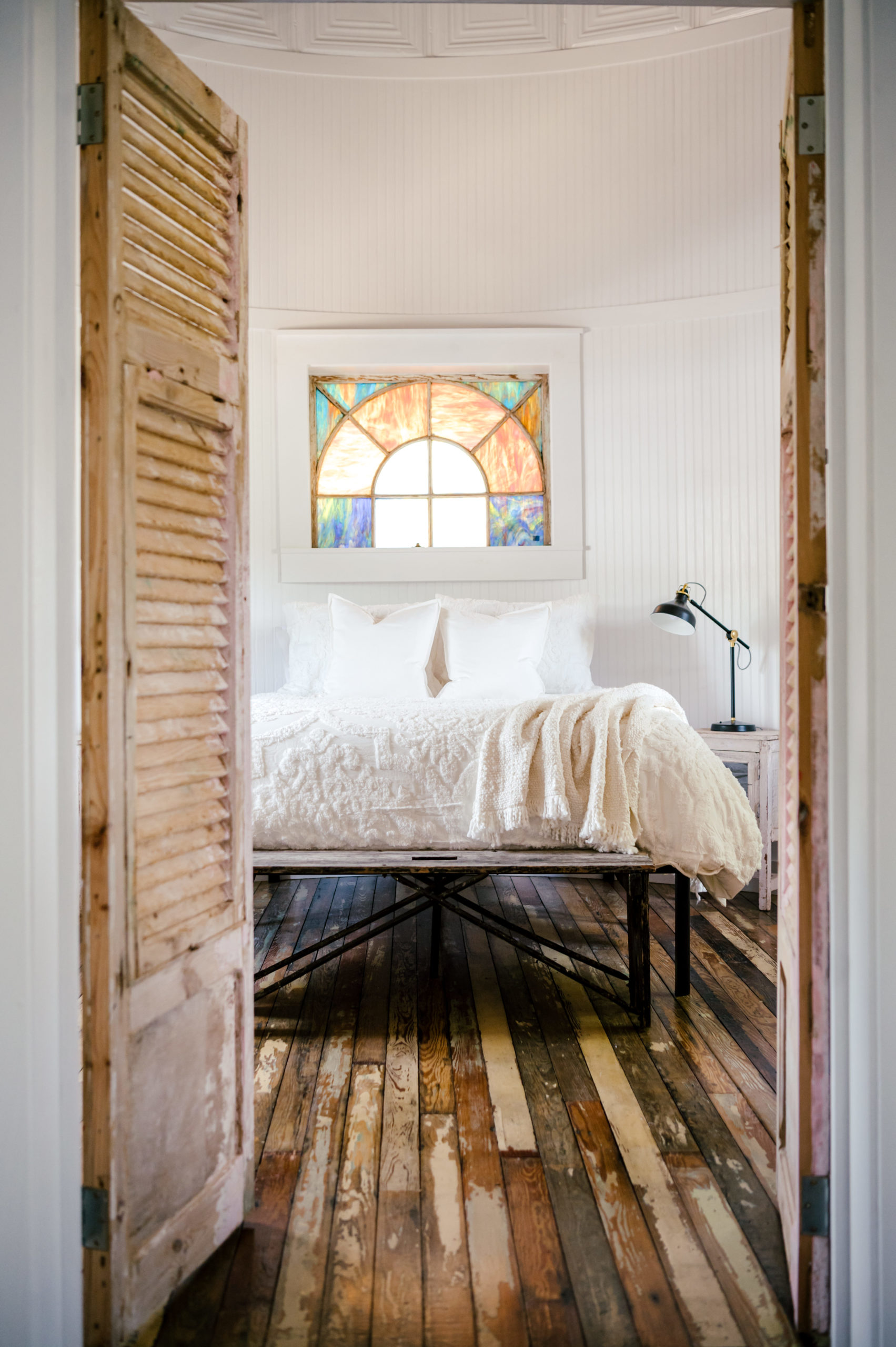 Airbnb Photography of doorway into bedroom with queen sized bed and stain glass window