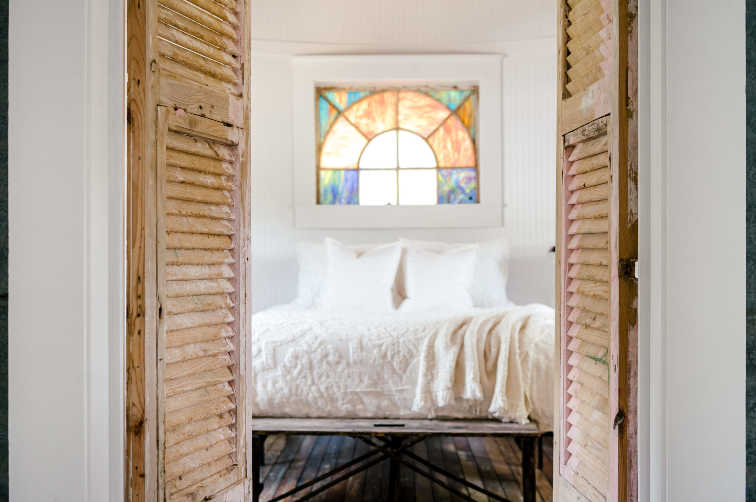 Airbnb Photography of doorway into bedroom with queen sized bed and stain glass window