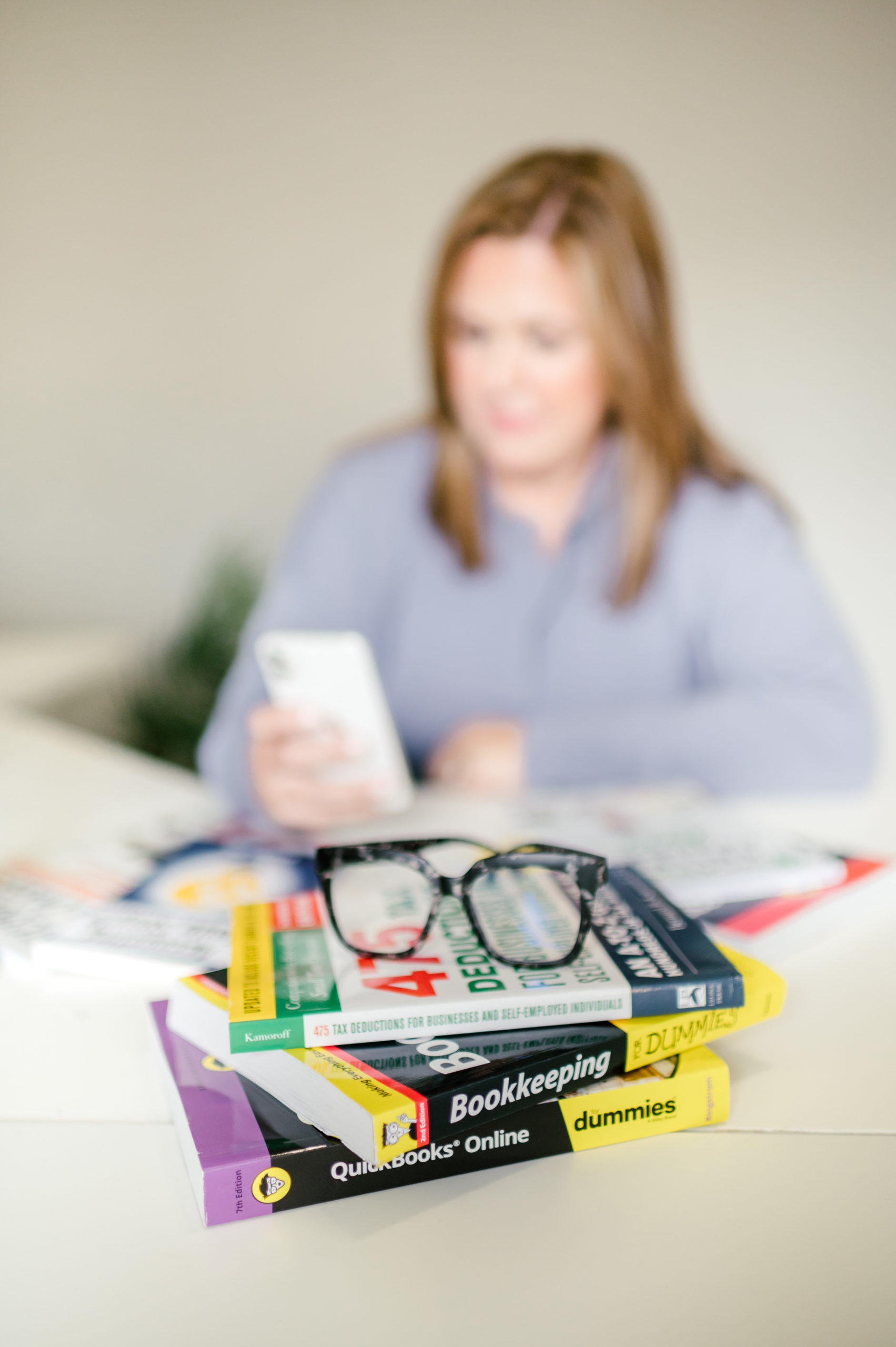 CPA business books sitting on top of a desk with a pair of reading glasses