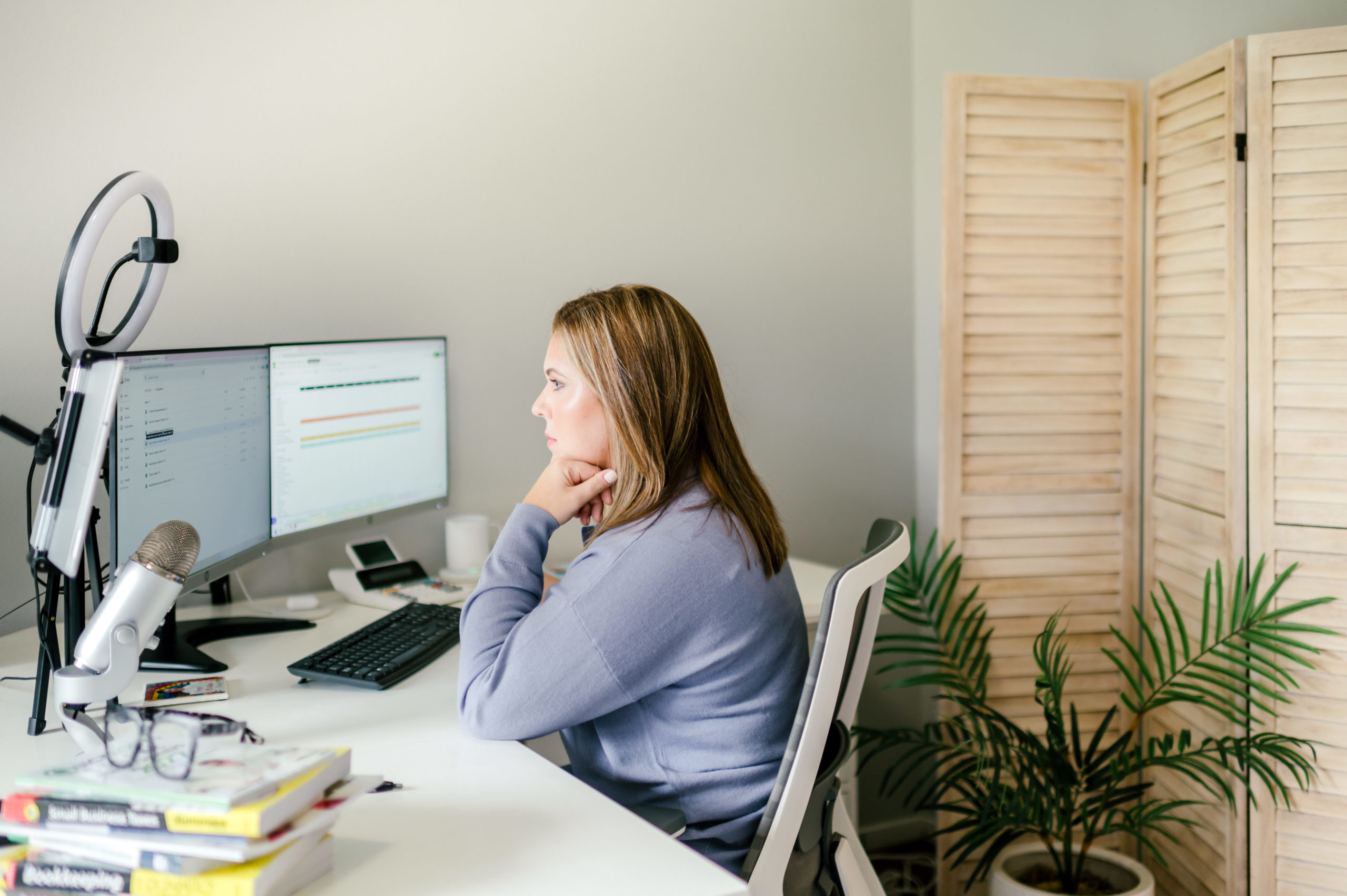 CPA business woman looking at computer screens working at desk in her office