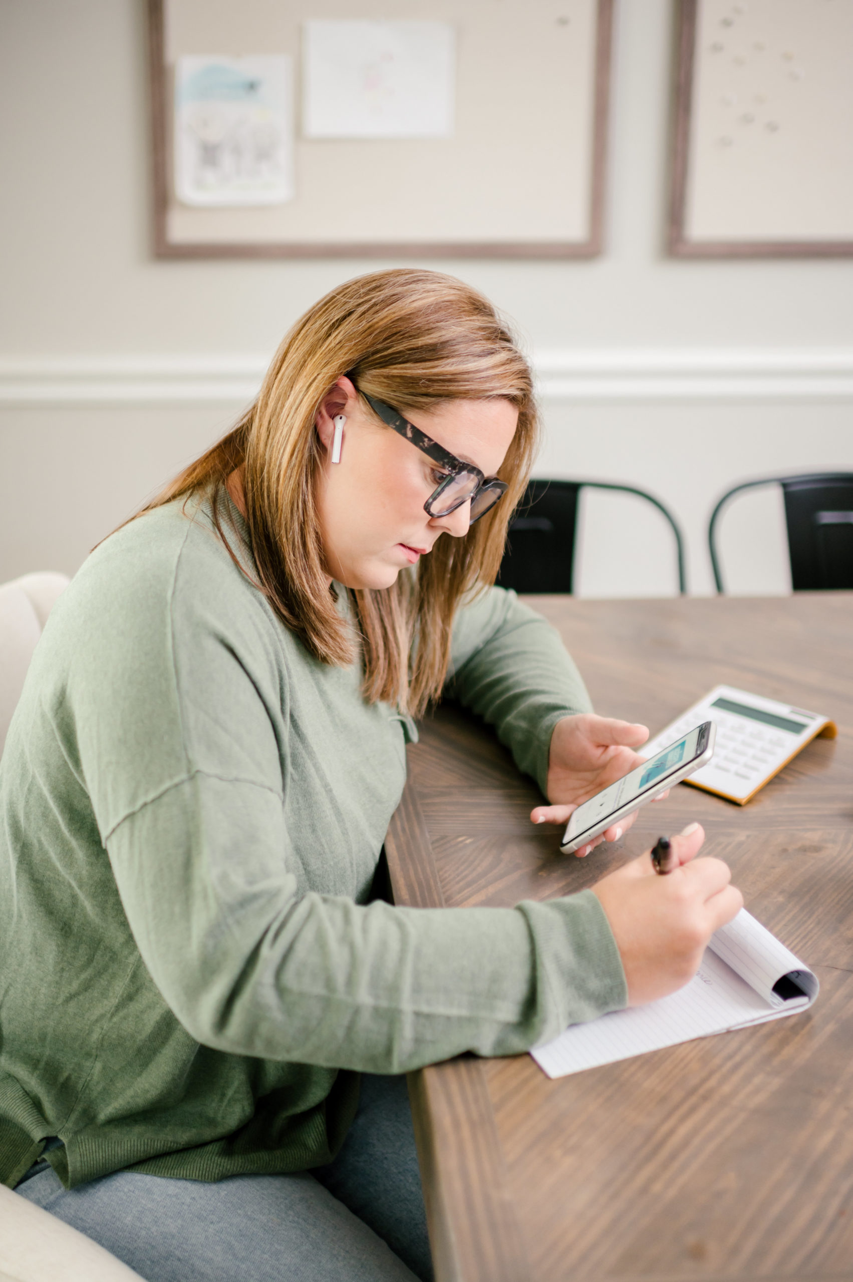 Small Business Branding Photography of CPA business woman sitting at dining room table taking notes on a notepad