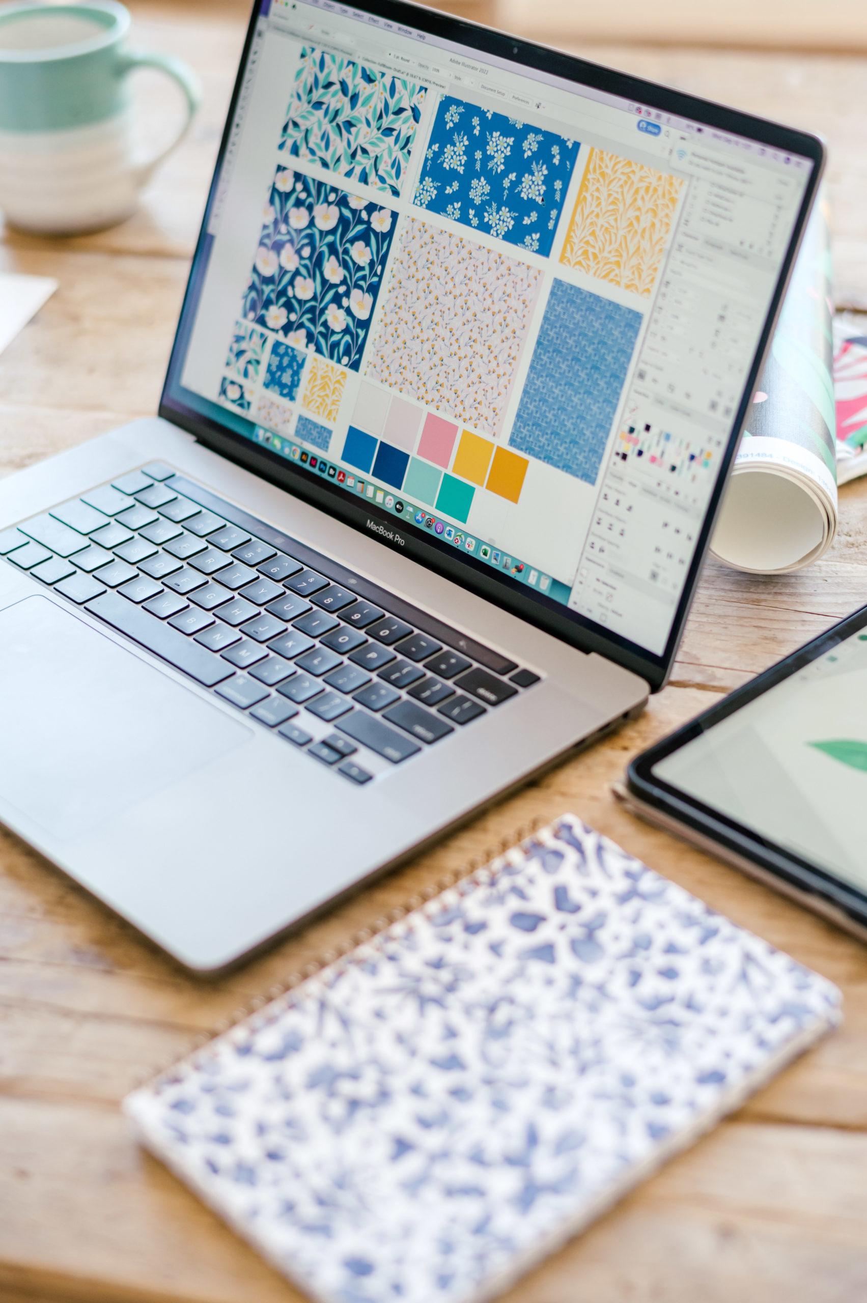 Laptop sitting on wooden table with illustrations of designs