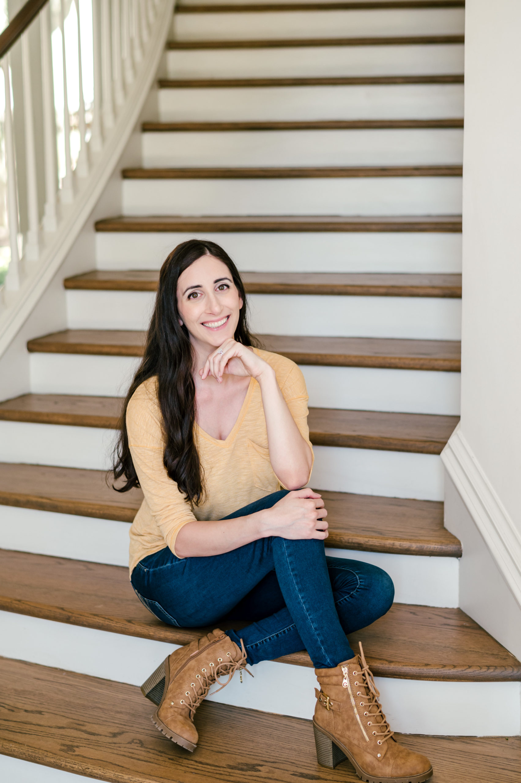 Woman designer sitting on the bottom of a staircase smiling for her branding session