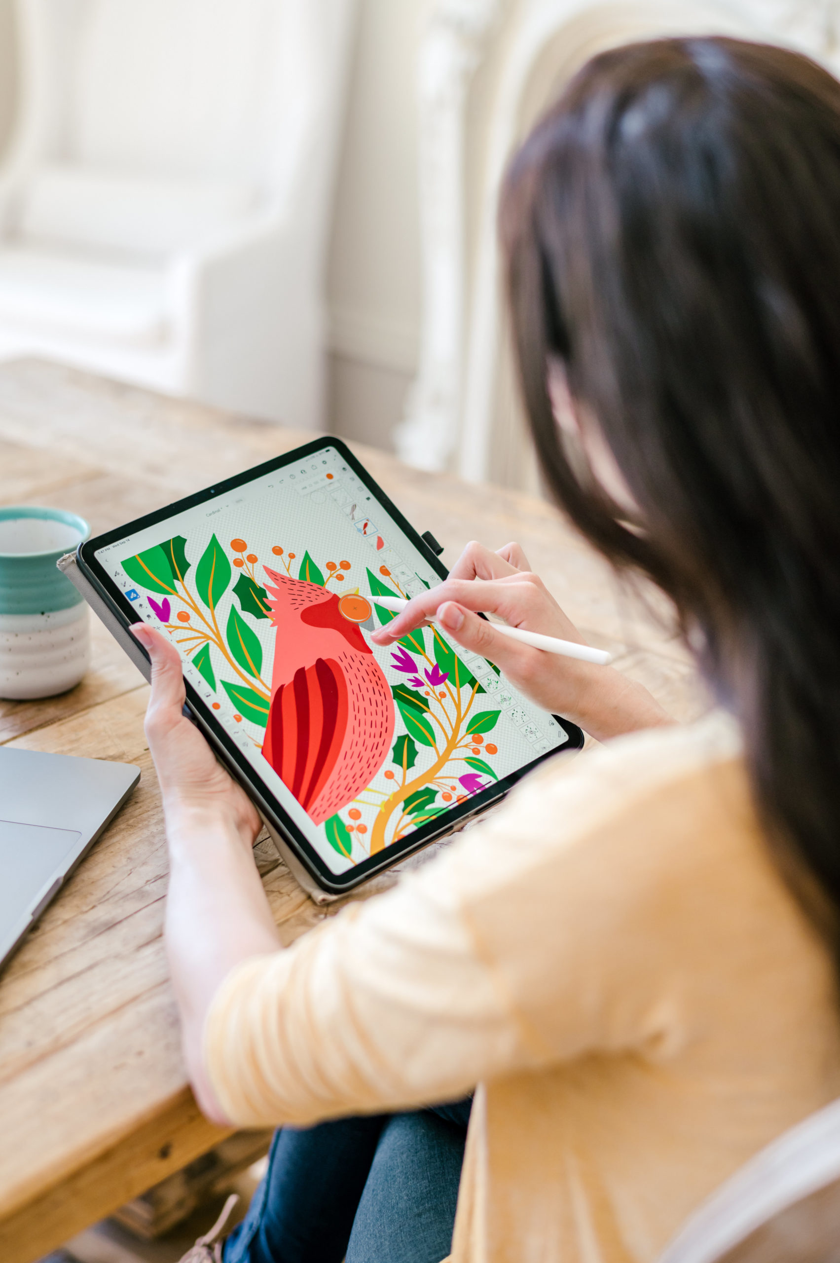 Woman designer designing illustrations of a red bird on her iPad