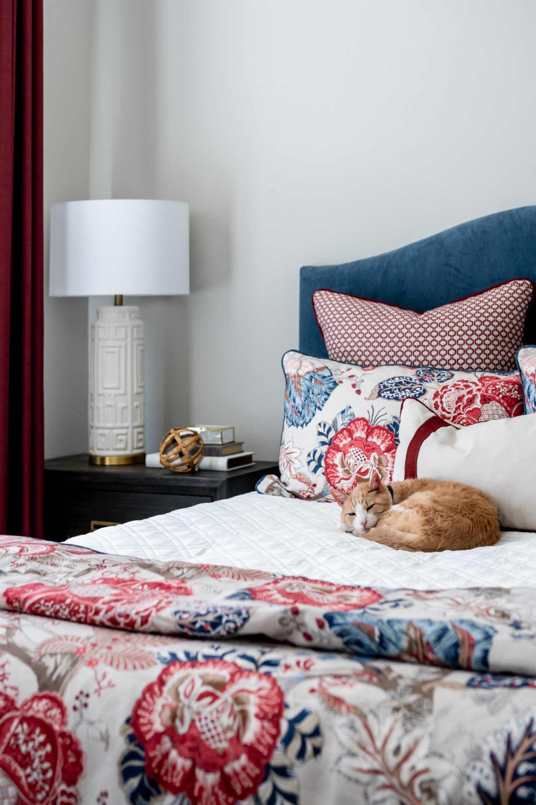 Beautiful bedroom interior design with floral bed covers and a cat sleeping