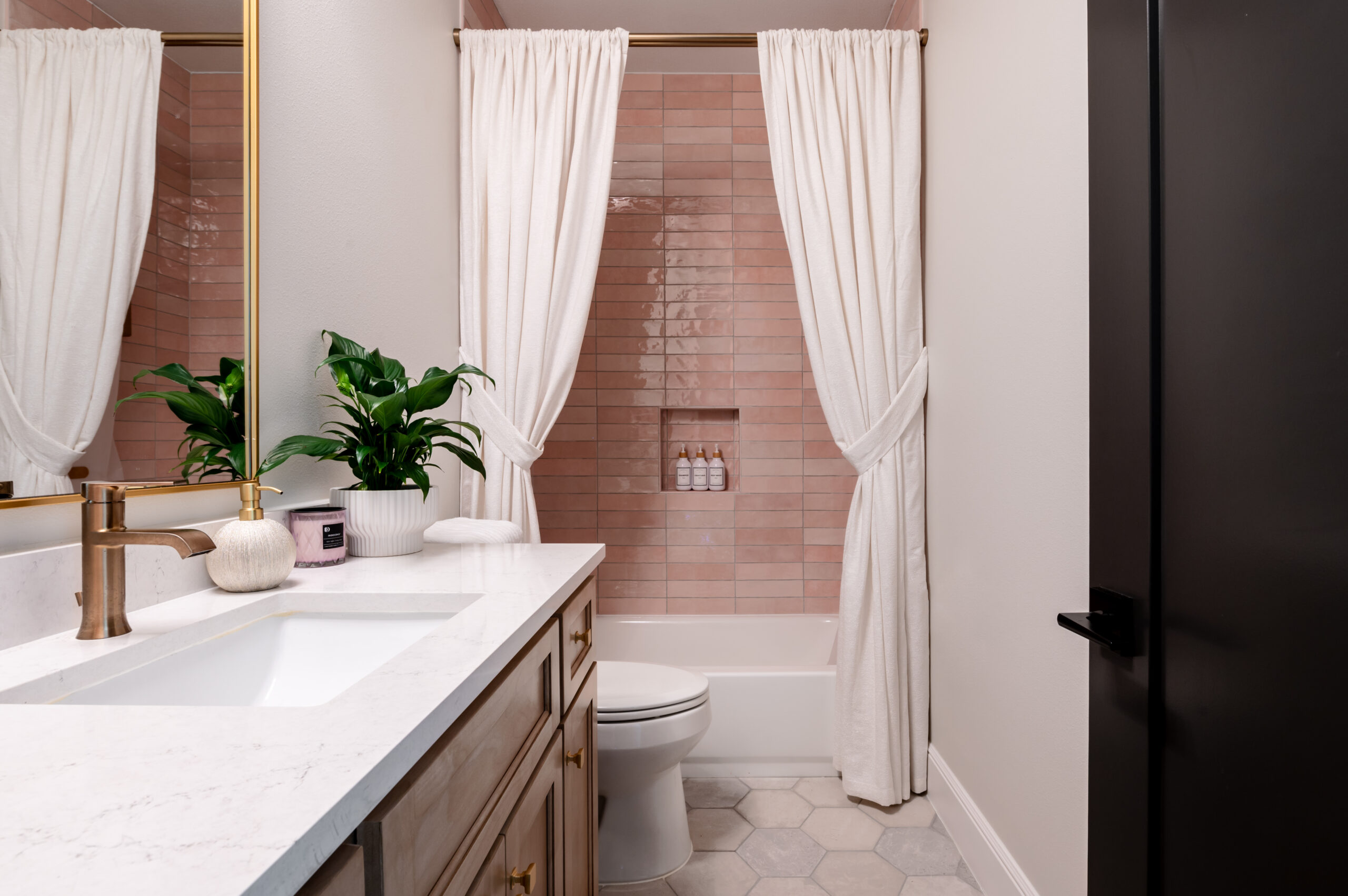 Bathroom interior with marble counters and pink shower backsplash