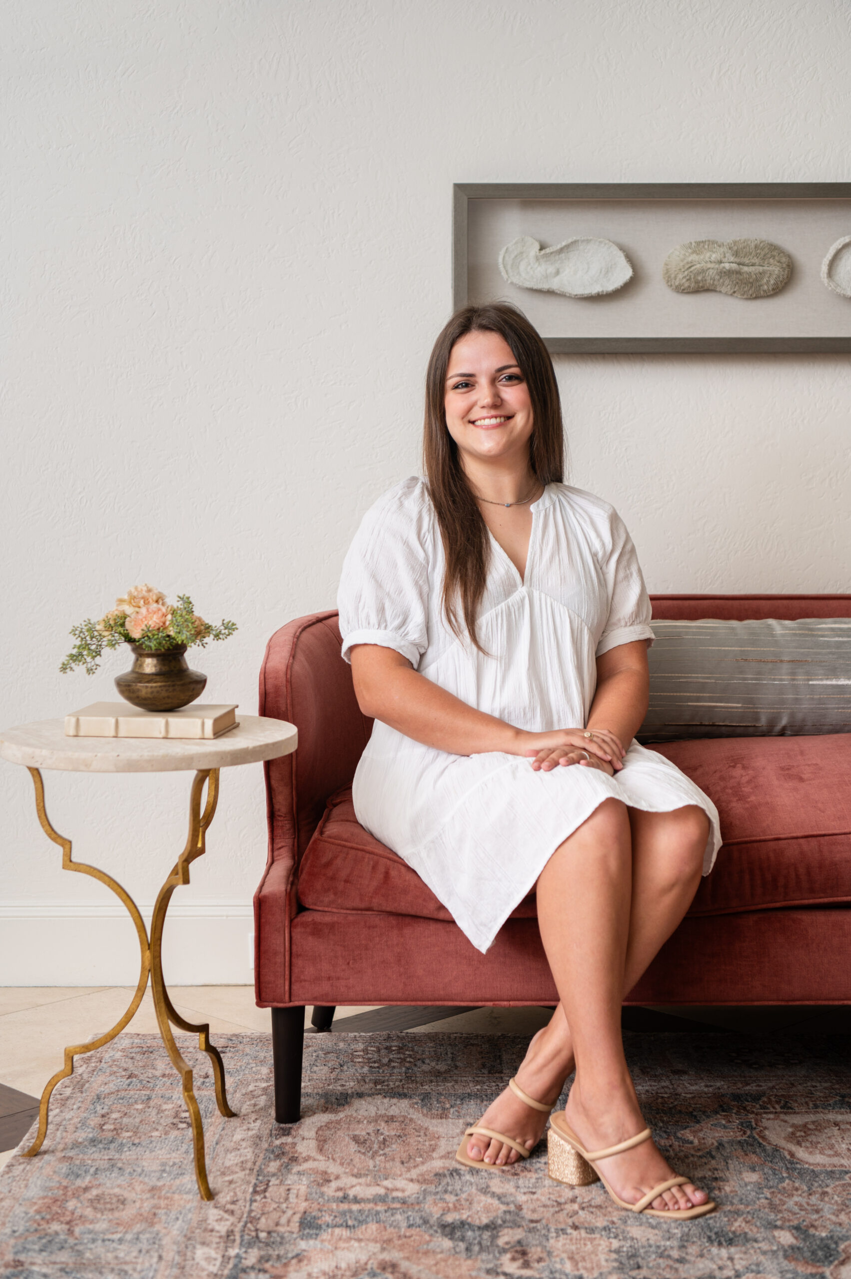 Interior design branding photo of a woman sitting on a red velvet couch