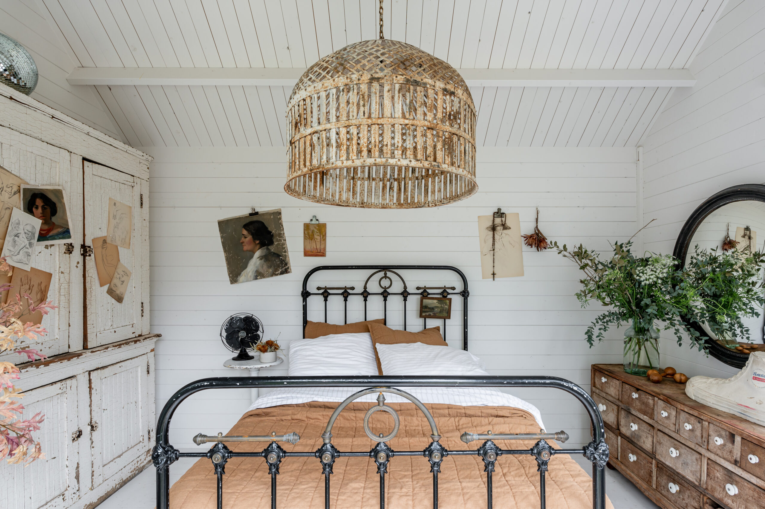 Beautiful bedroom interior with vintage bed frame and bedroom drawer, antique wall art and side table