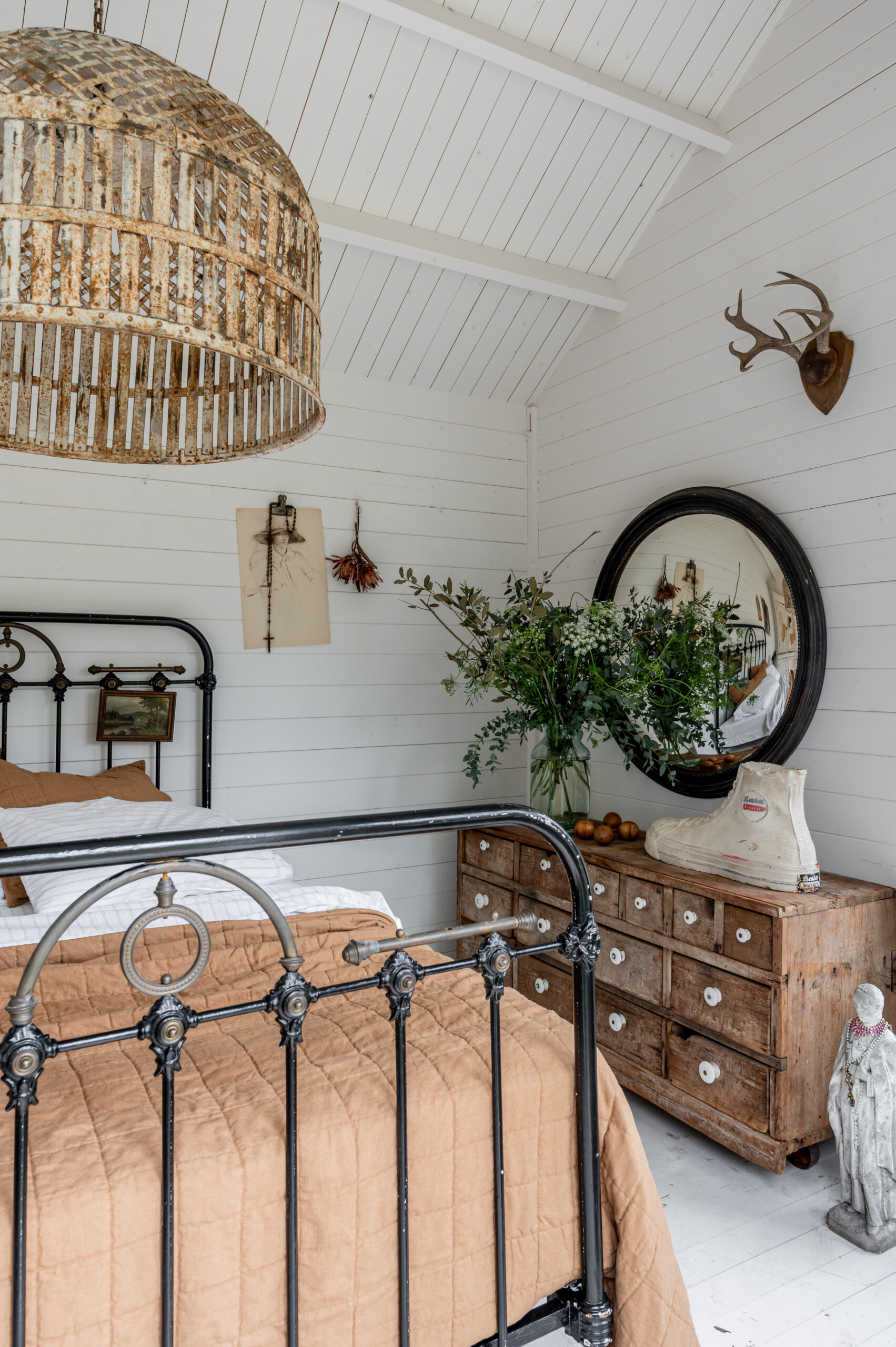 Beautiful bedroom interior with vintage bed frame and antique wall art and side table