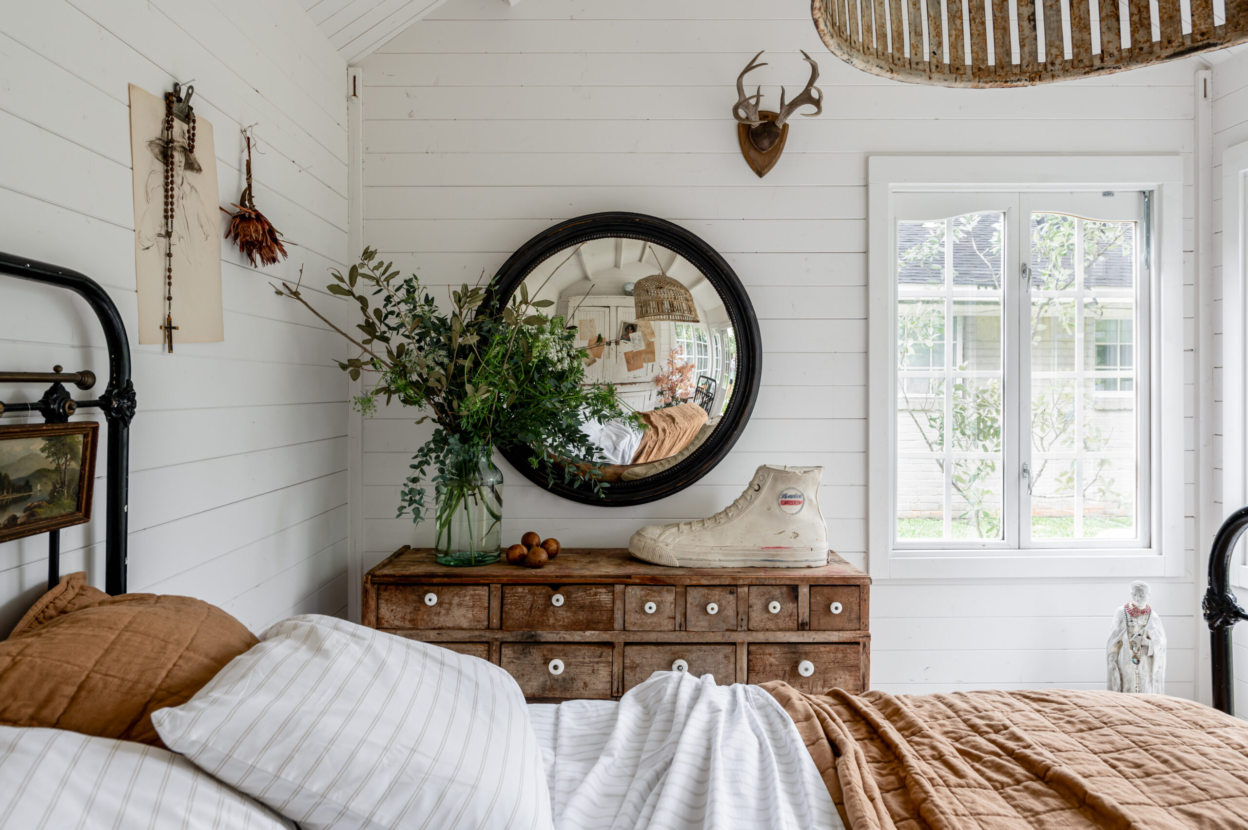 Beautiful bedroom interior with vintage bed frame and bedroom drawer, antique wall art and side table