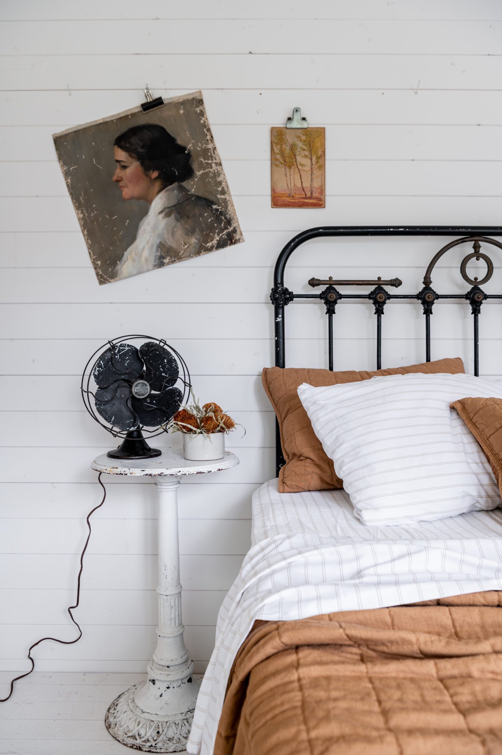 Beautiful bedroom interior with vintage bed frame and antique wall art and side table