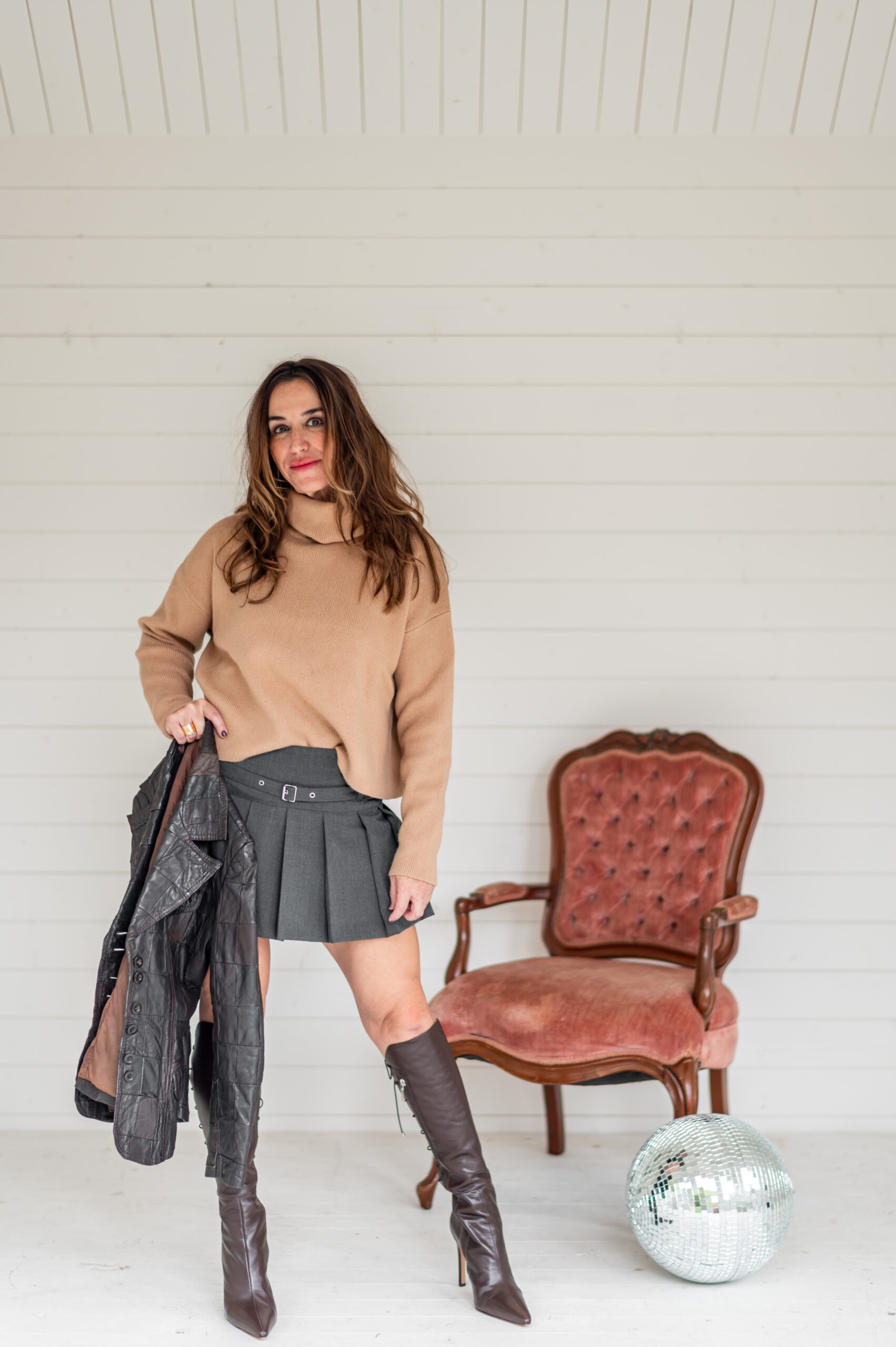 Woman standing near vintage chair posing for her business launch photoshoot