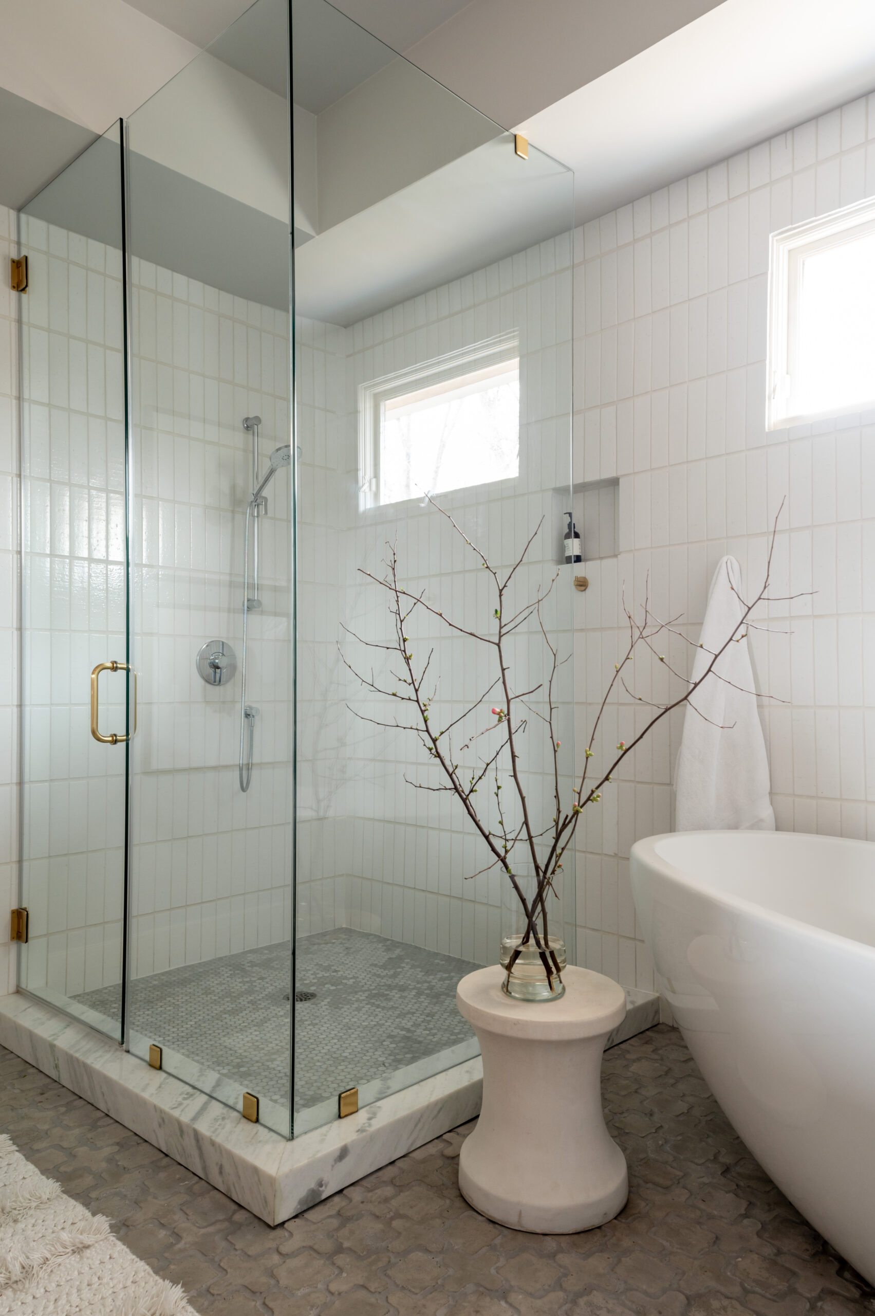 Stunning white bathtub and shower in a luxury tiled bathroom