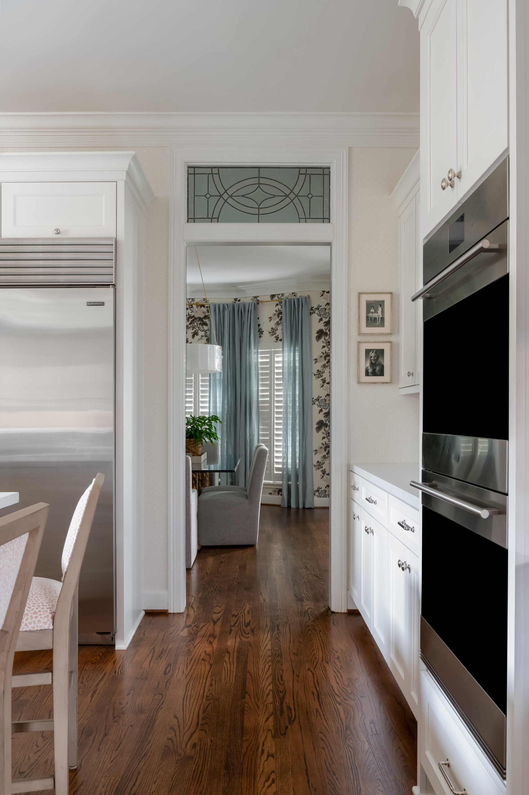 Kitchen interior photo looking into dining room with all white cabinets and furniture