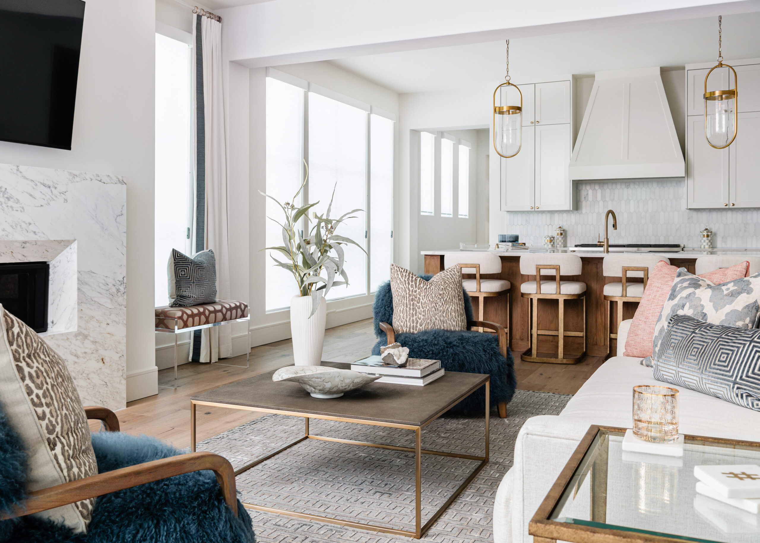 Open concept living room and kitchen: A modern, airy Texas interior design living room with cozy, plush seating, a chic coffee table, and a view of the open-concept kitchen featuring white cabinetry and warm wood elements.