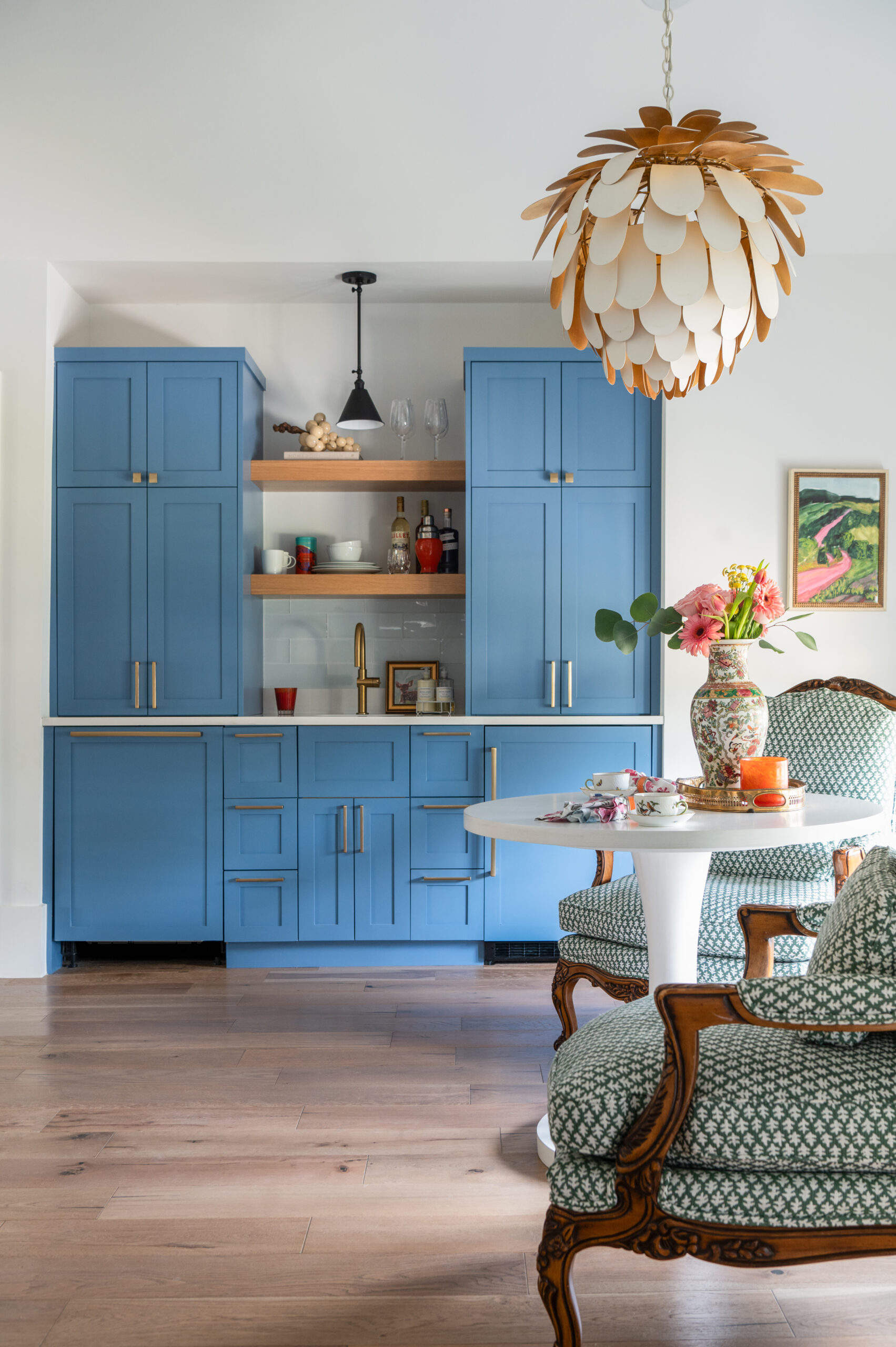 Image of a modern kitchen with blue cabinetry, a pendant light, and vibrant decor.
