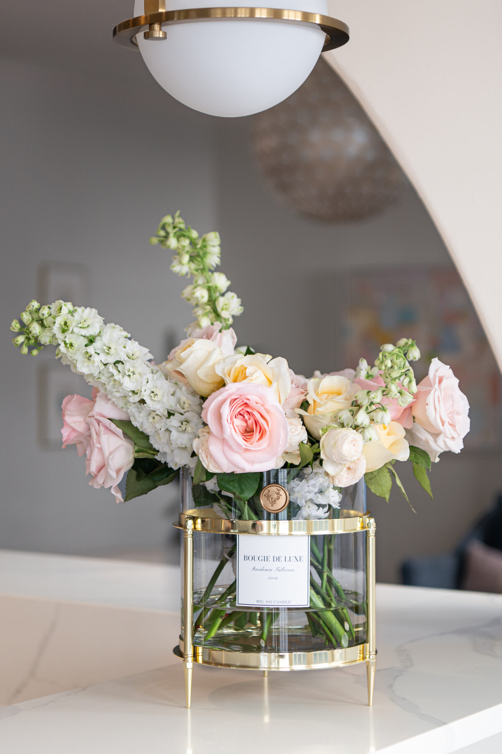 A close-up of beautiful floral arrangements with a candle, elegantly arranged in a living room corner, highlighting the soft glow and serenity in seasonal photography.

