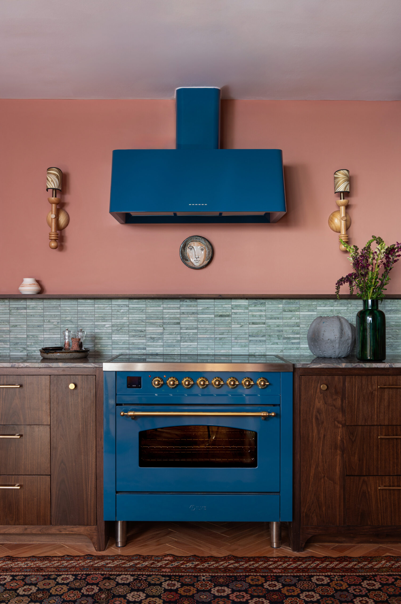 Symmetrical shot of a vibrant blue oven and hood surrounded by dark wood cabinetry and sage green backsplash—perfect for learning how to photograph interior spaces with symmetry and color contrast.
