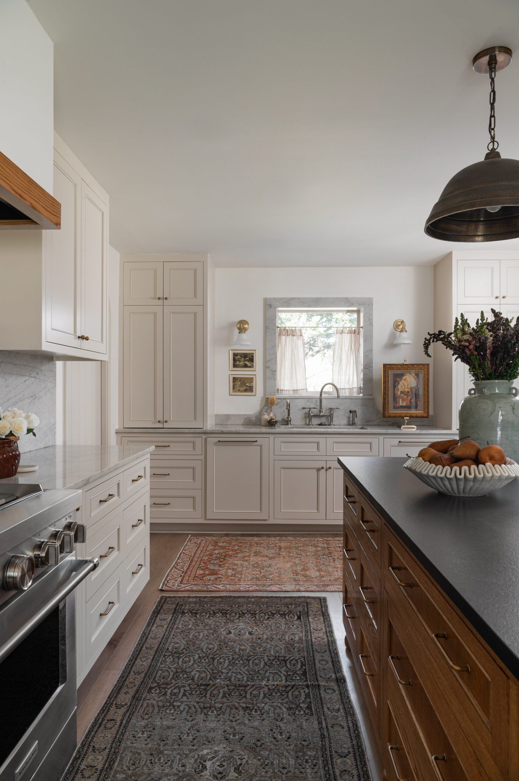 A cozy kitchen window scene with layered rugs, soft cabinetry tones, and stone counters—showing how to photograph interior spaces that evoke warmth and story.