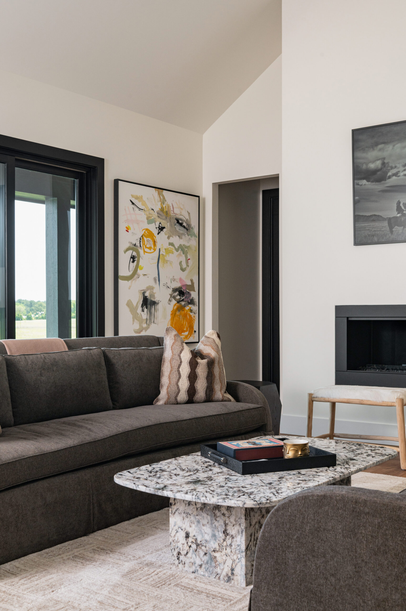 Visual storytelling photography of a modern living room with soft earth tones, an abstract art piece, and a marble coffee table layered with books and a brass candle.