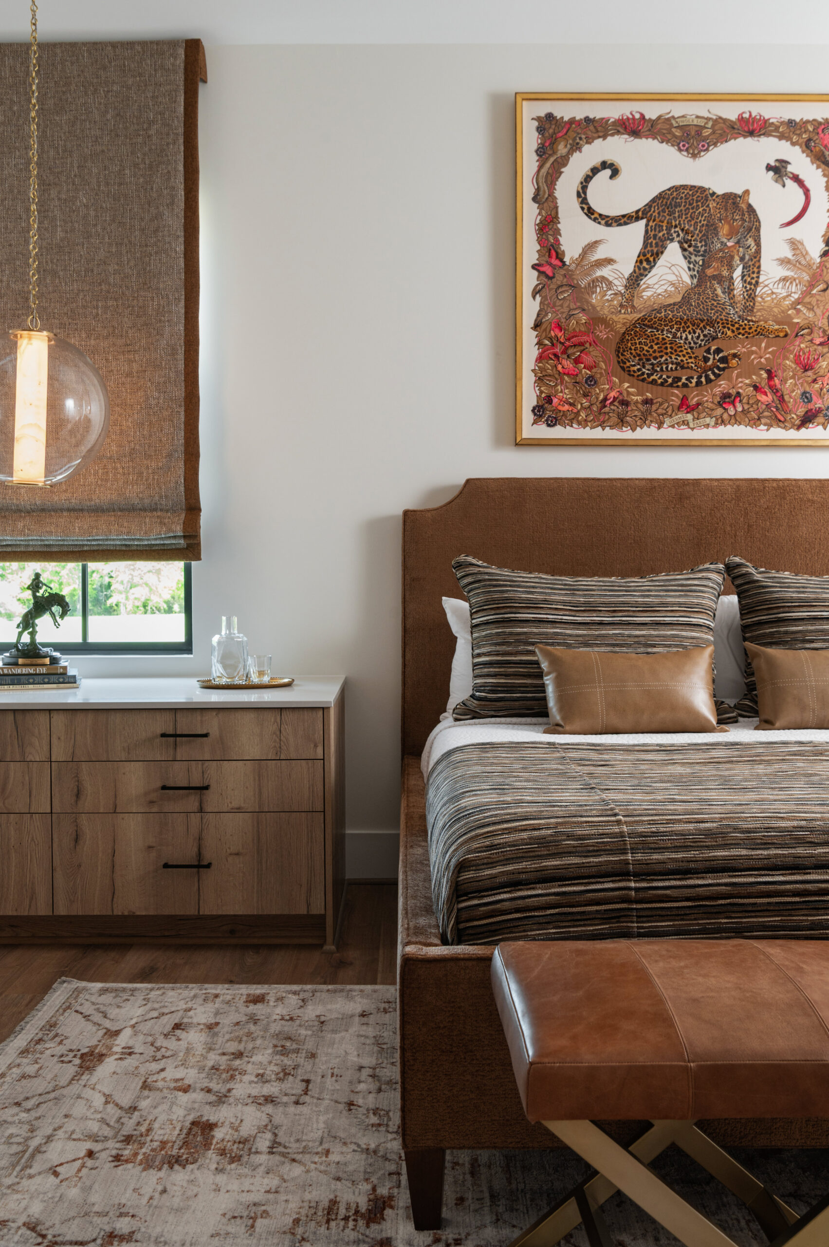  Visual storytelling photography of a cozy bedroom that combines earth tones, animal art, and striped bedding with leather accents for a rich, layered feel.