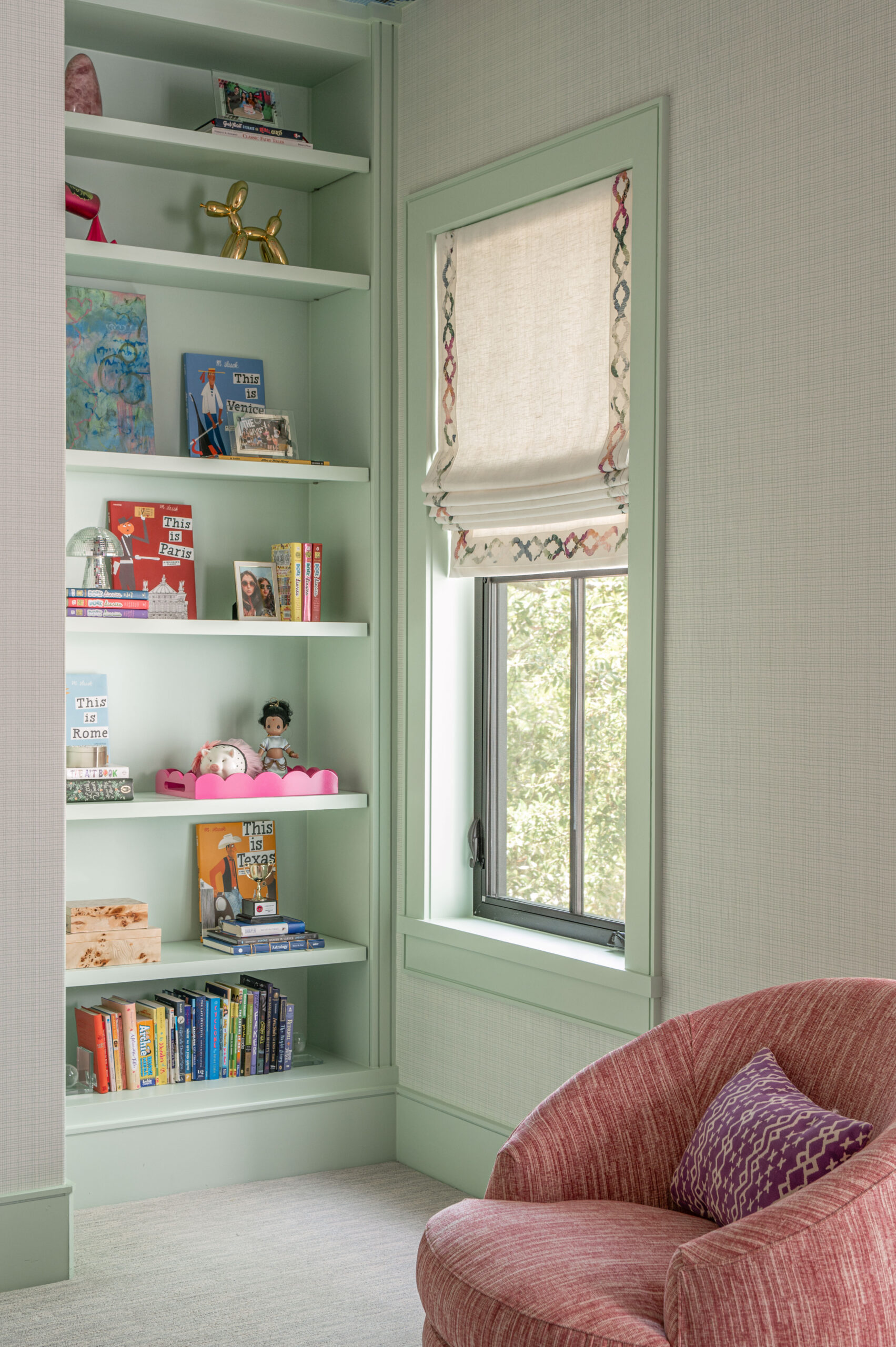 Built-in mint green bookshelves filled with colorful books and playful toys, perfect for a tween’s room.