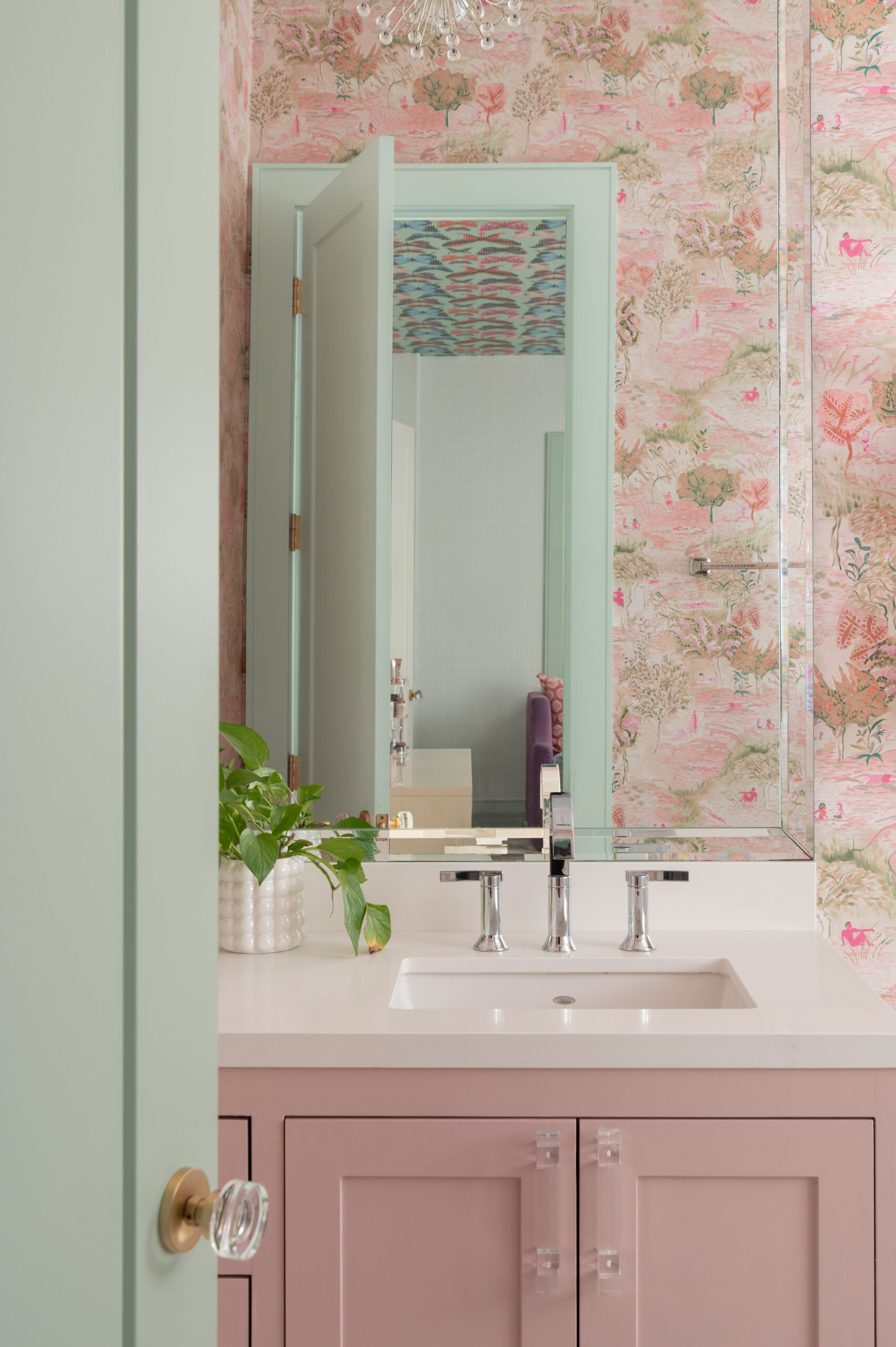 Bathroom detail with a modern white vanity, pink cabinetry, and floral wallpaper reflecting the fun of a tween's space.