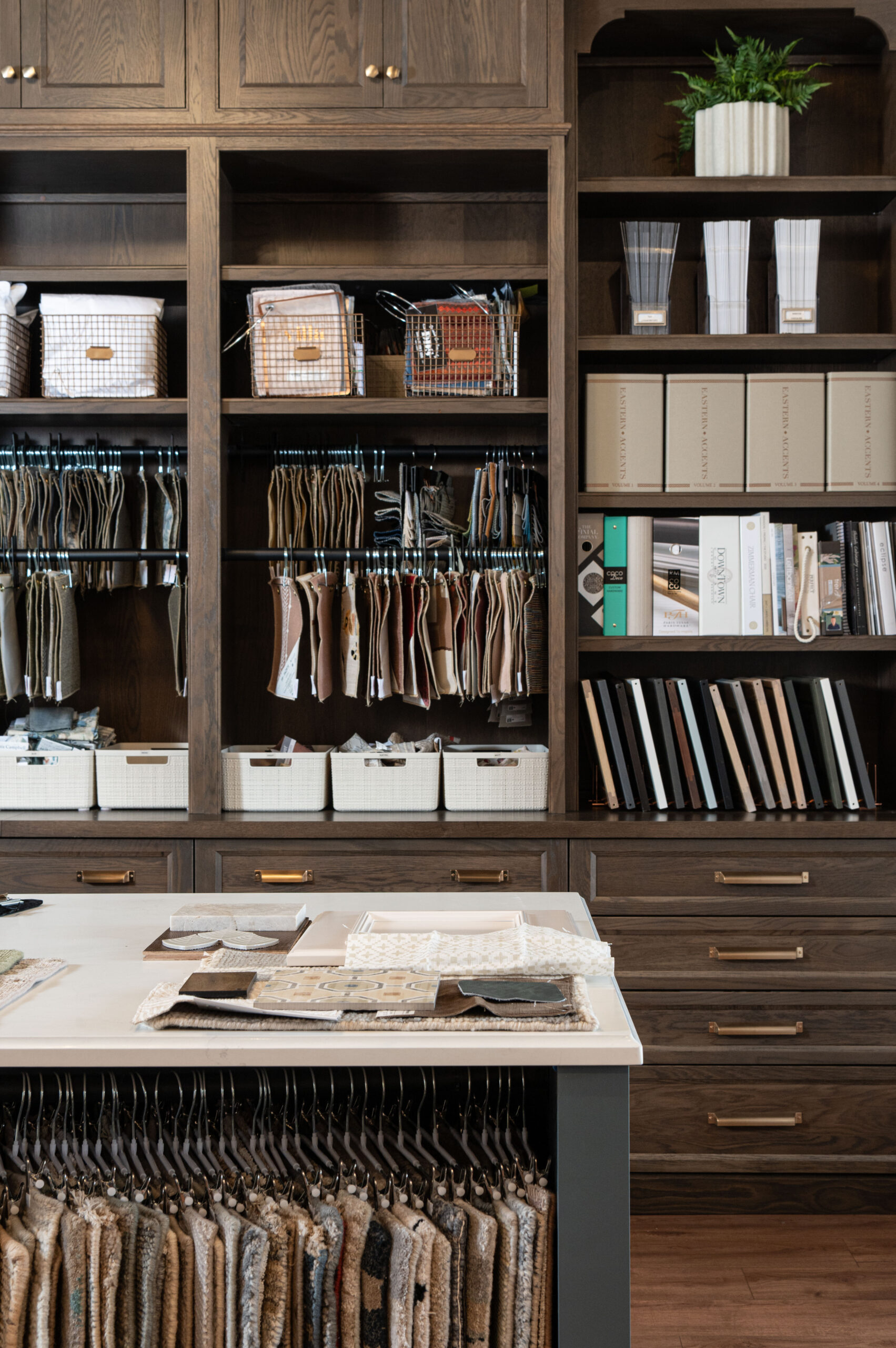 Organized shelving filled with fabric swatches, samples, and design resources in a professional interior design studio.