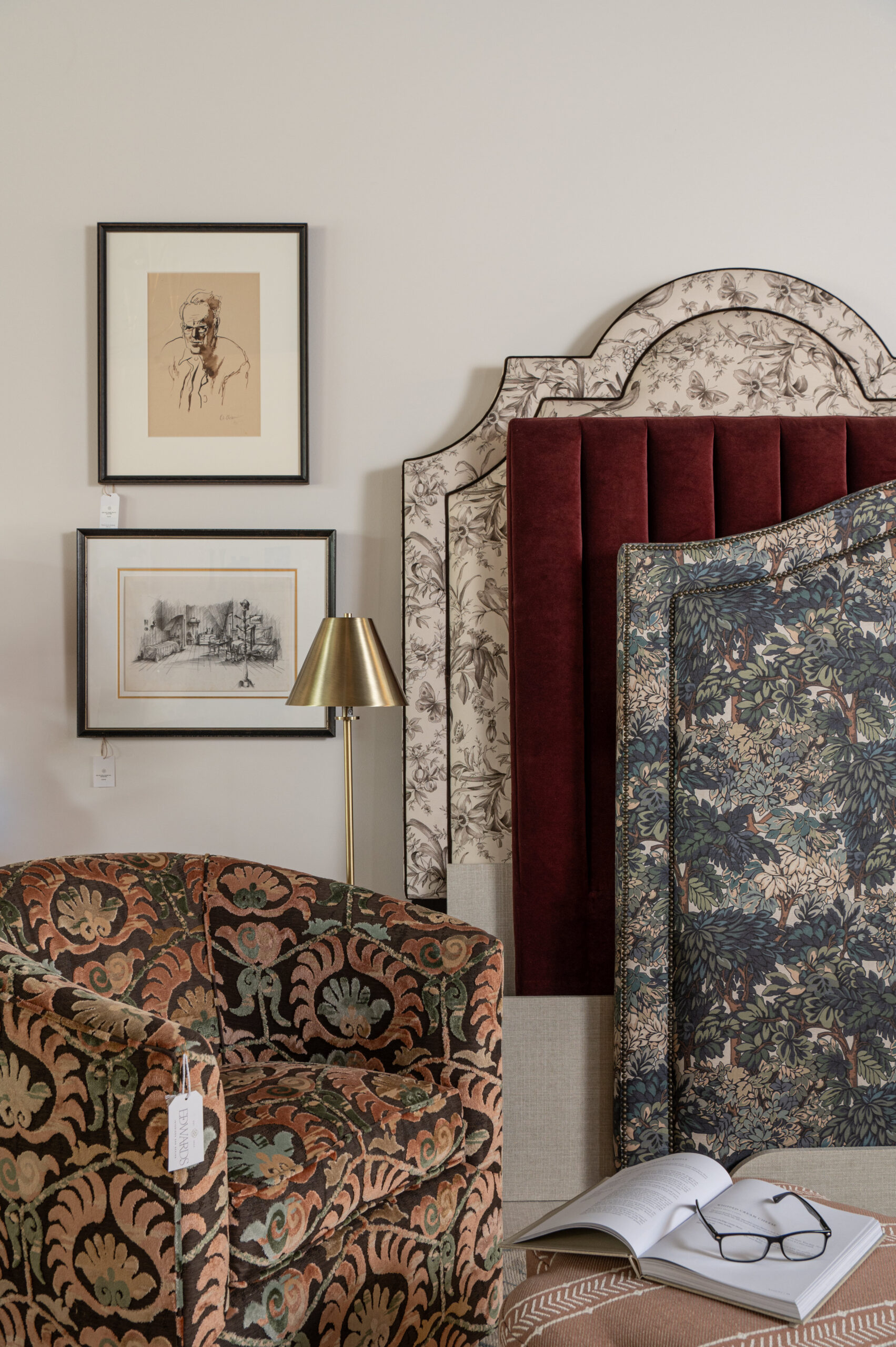 A corner of a design studio with bold patterned upholstery, custom headboards, and framed sketches, highlighting rich textures and curated decor.