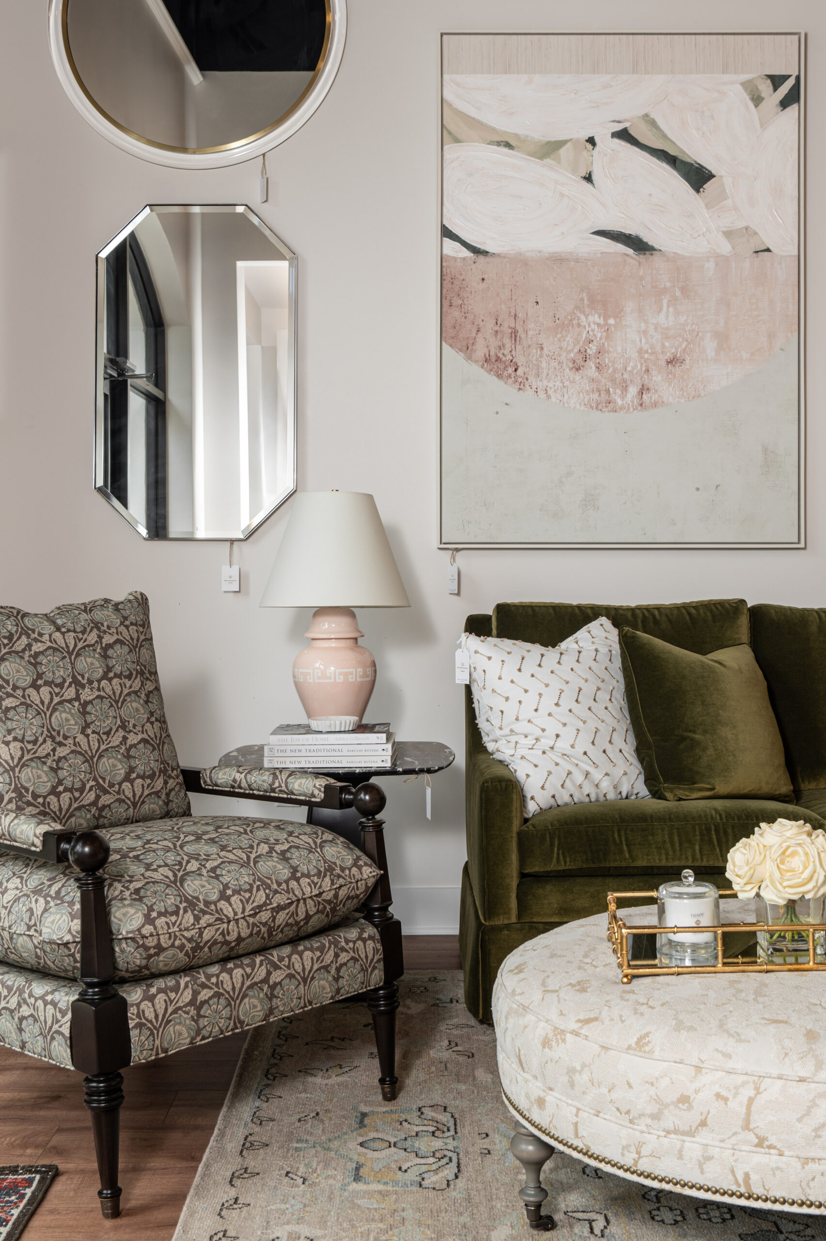 Sophisticated living room vignette featuring an olive green velvet sofa, floral upholstered armchair, layered mirrors, and abstract wall art.