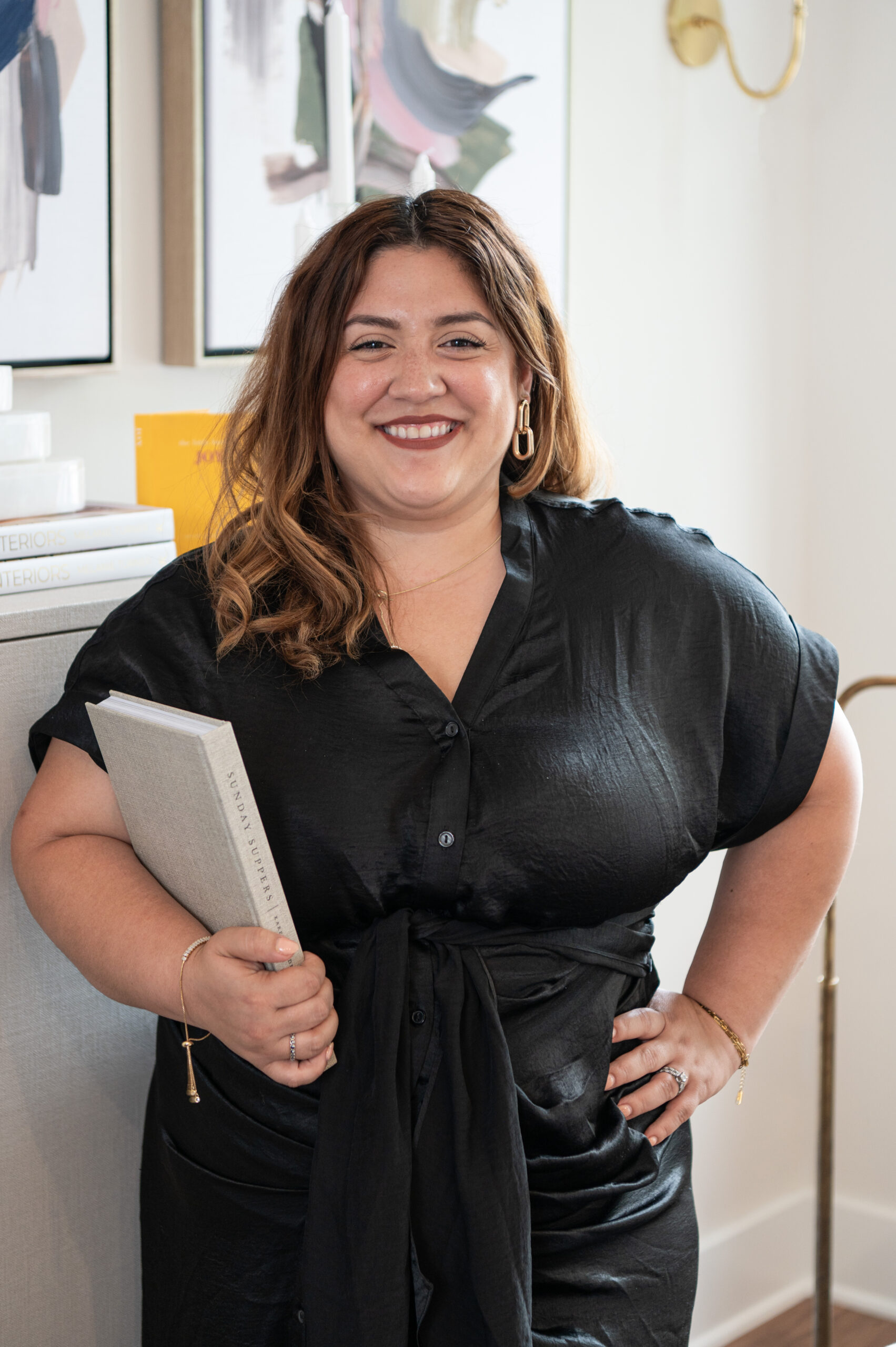 Interior designer smiling while holding a design book, styled by an Austin brand photographer to showcase personality and professionalism.
