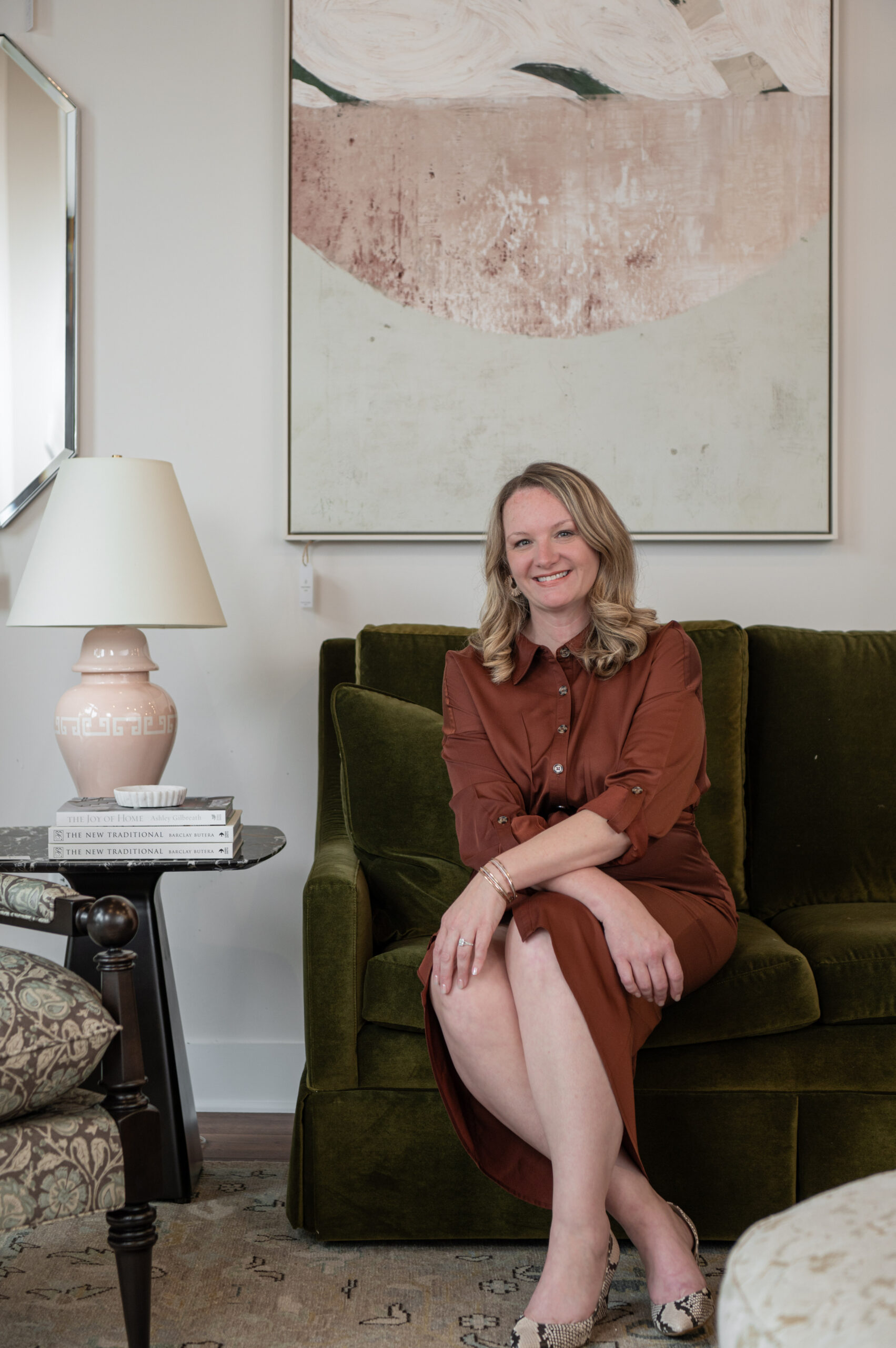 Interior designer sitting on a green velvet couch in a curated living room setting, highlighting her personality through thoughtful brand photography.