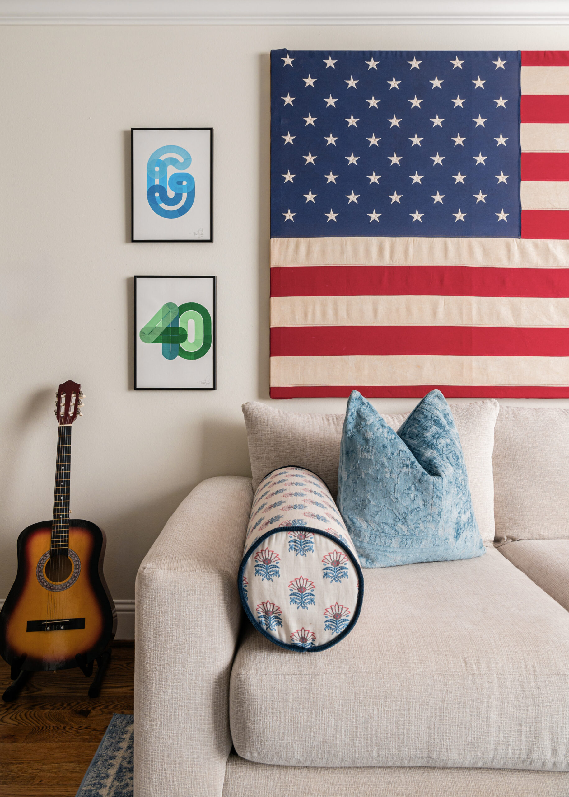 Cozy corner of a living room with an American flag wall hanging and a beige couch, showcasing playful styling interior design.