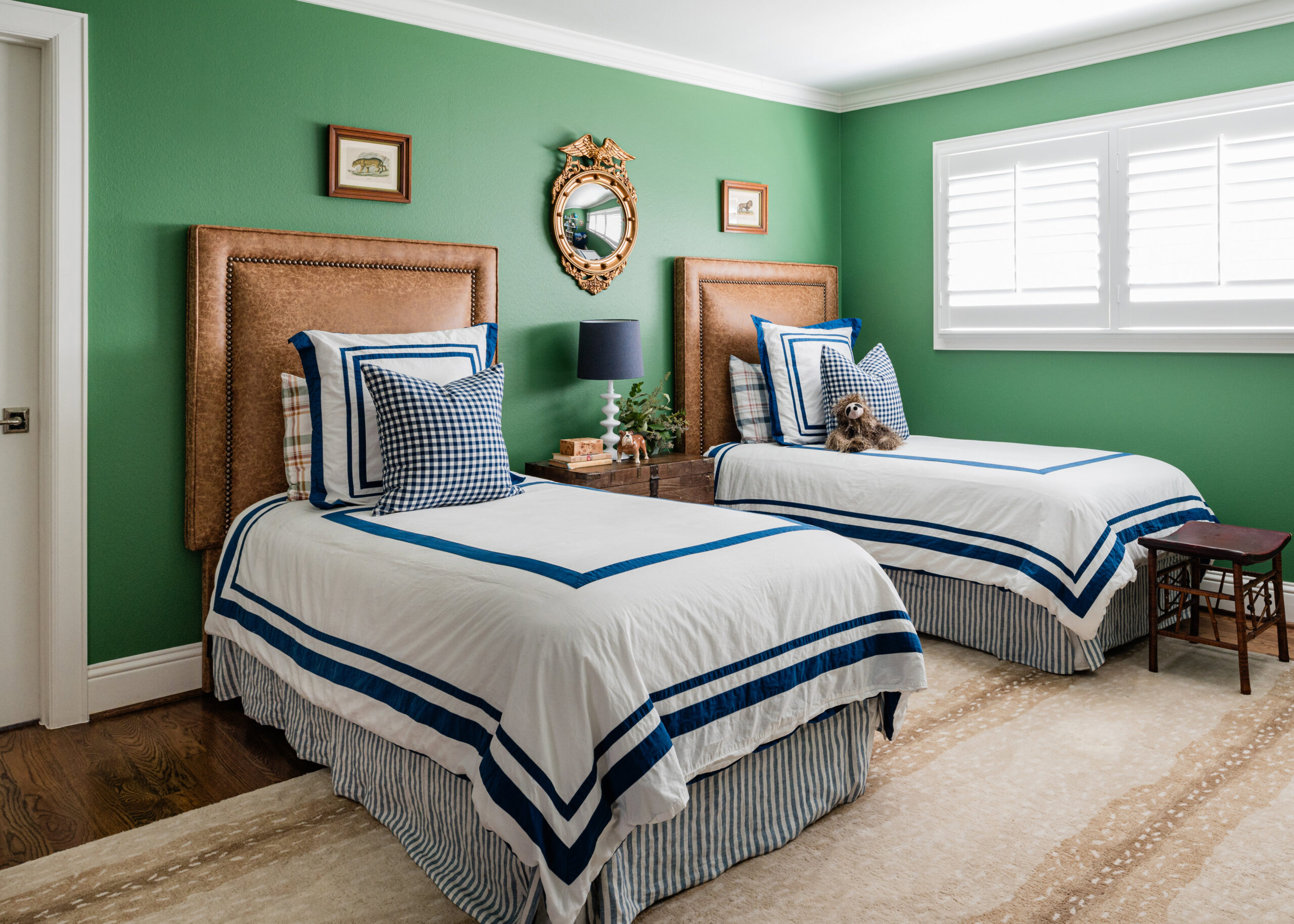 Bright and playful twin bedroom with bold green walls, rattan headboards, and navy-accented bedding, showcasing thoughtful styling interior design for a children’s room.