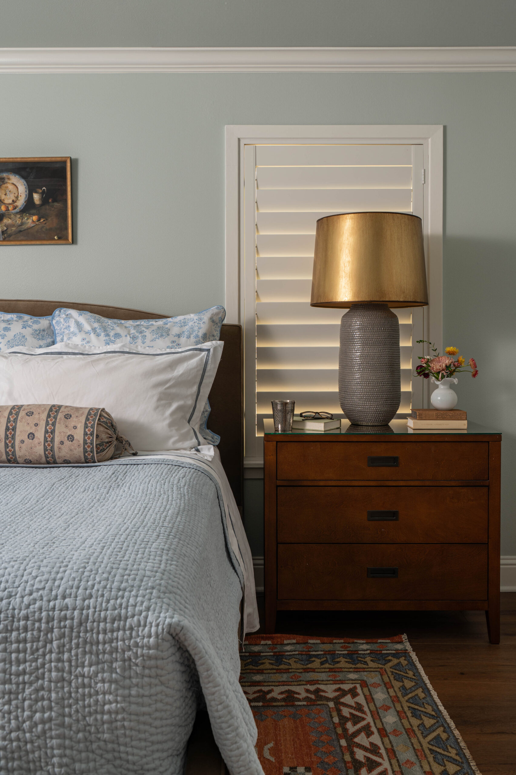 Warm-toned bedroom with a patterned red rug, upholstered bed, and traditional decor in a cozy modern cottage.
