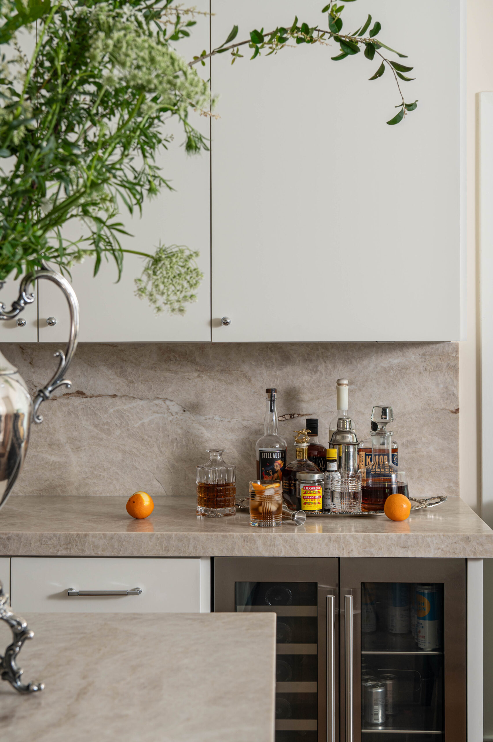 Close-up of a kitchen range with copper cookware, natural stone backsplash, and fresh produce on the counter.