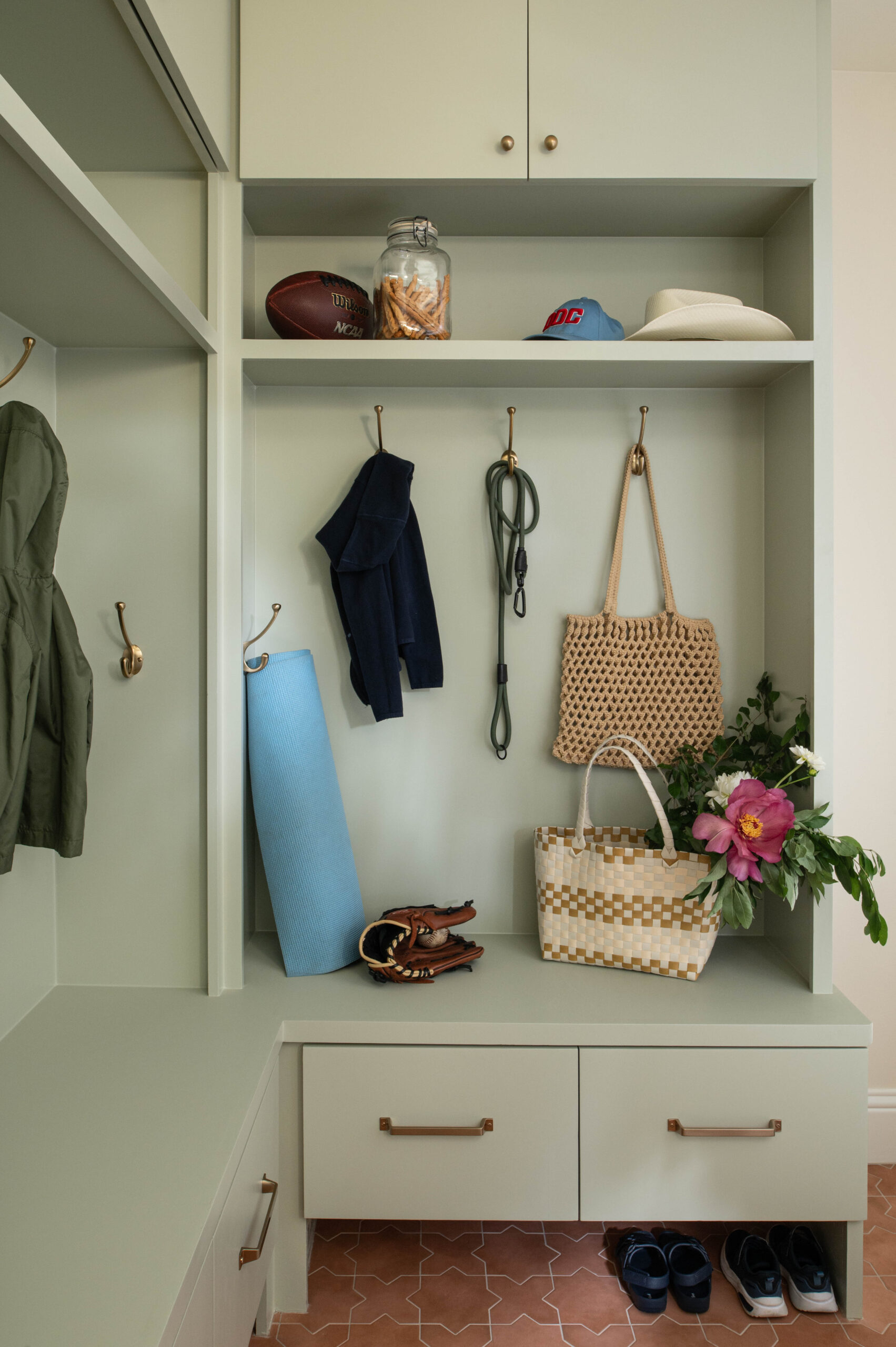 Functional mudroom styled with yoga gear, sunhats, and a fresh bouquet, offering a lived-in yet polished look.