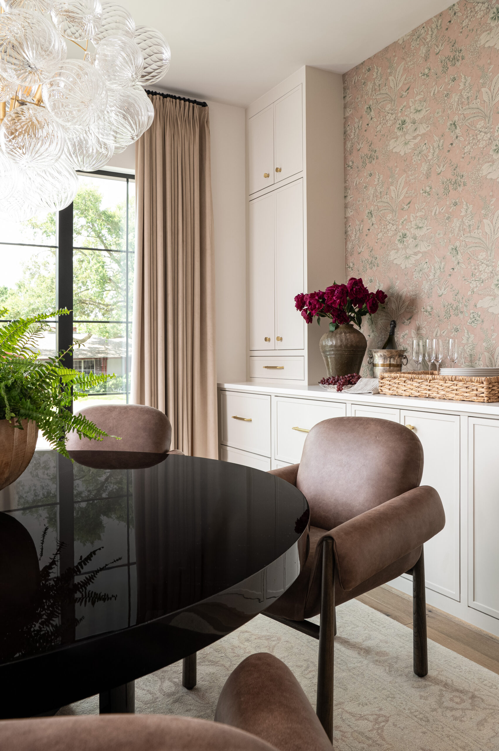 A dining area with floral wallpaper, soft velvet dining chairs, and sheer curtains, offering a soft, layered look that beautifully captures the importance of texture in interior design.