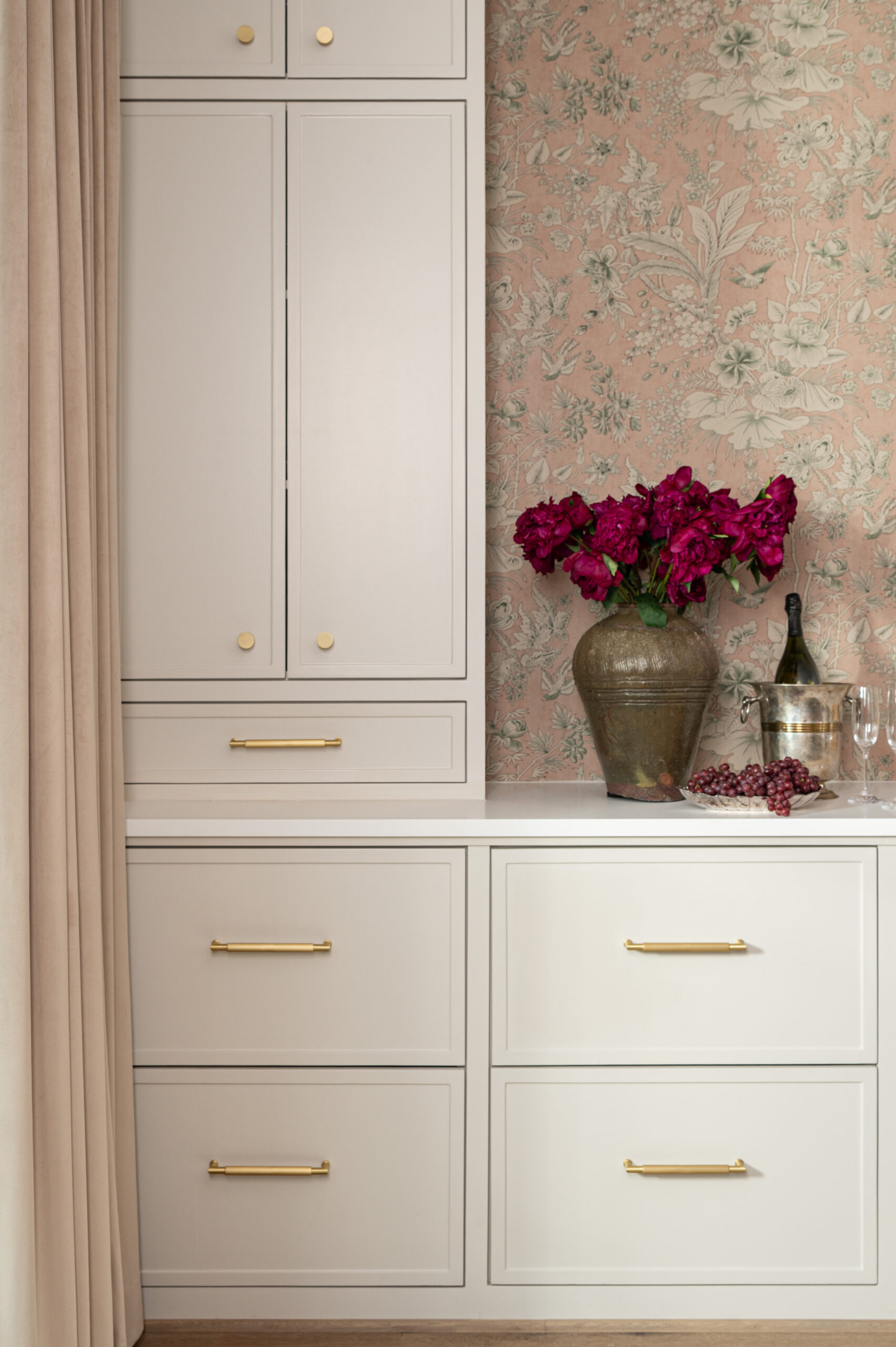 Floral wallpaper introduces soft texture in interior design, complementing creamy built-in cabinetry, brass hardware, and rich, organic accessories.