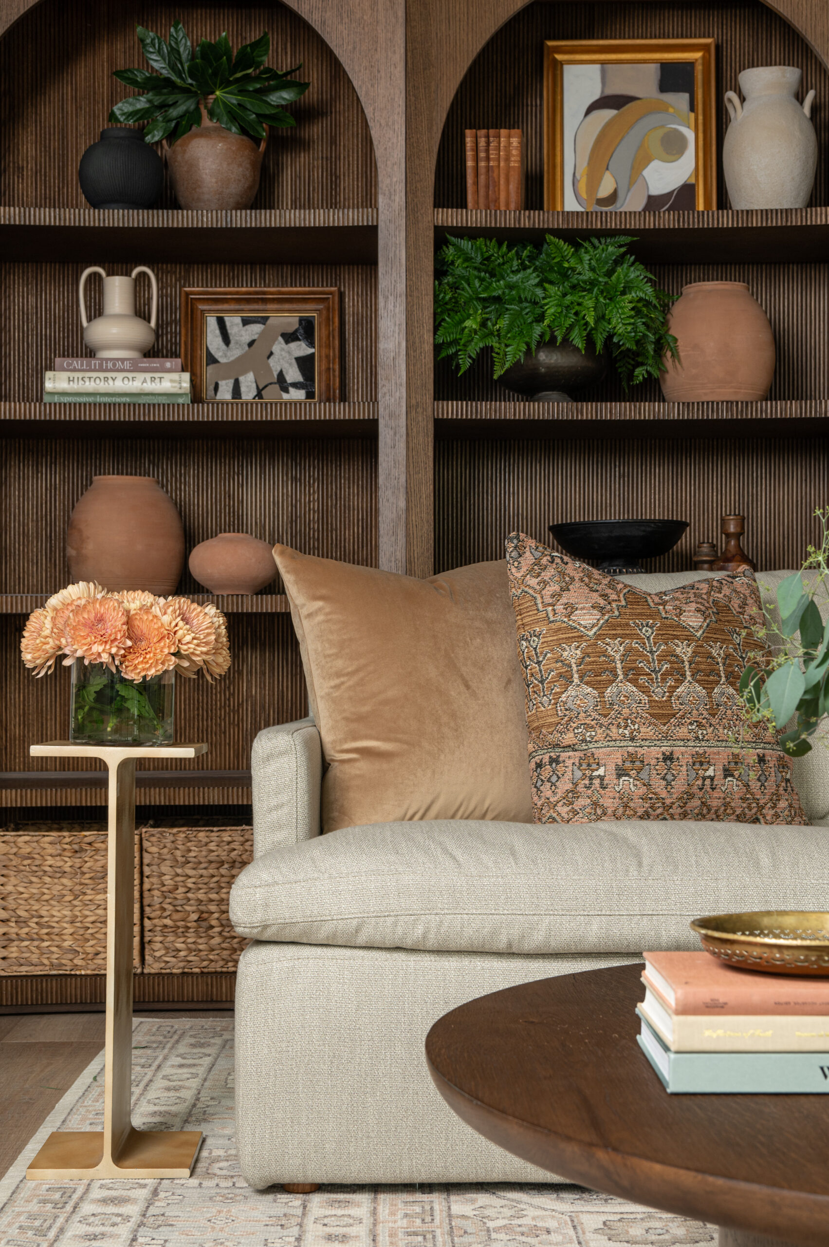 A cozy nook with a neutral sofa layered in plush velvet and woven pillows, surrounded by textured wood shelving—showcasing the impact of texture in interior design.