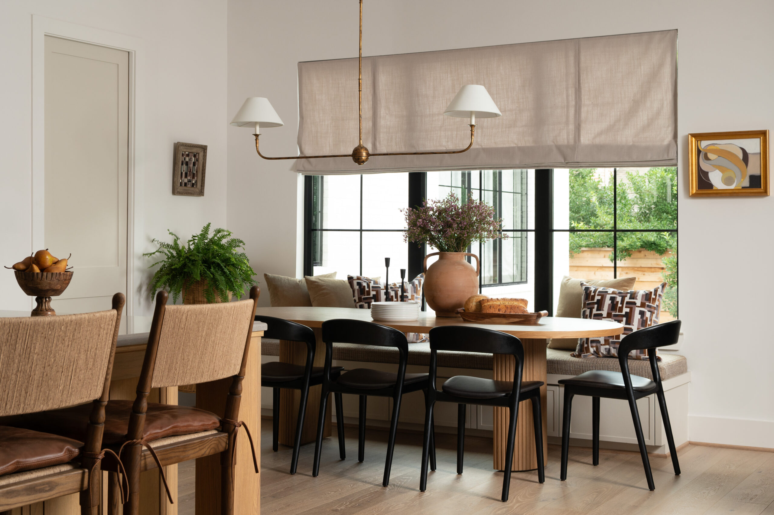 A modern kitchen with woven bar stools, leather seats, and natural wood tones, emphasizing texture in interior design by blending organic and refined materials throughout the space.

