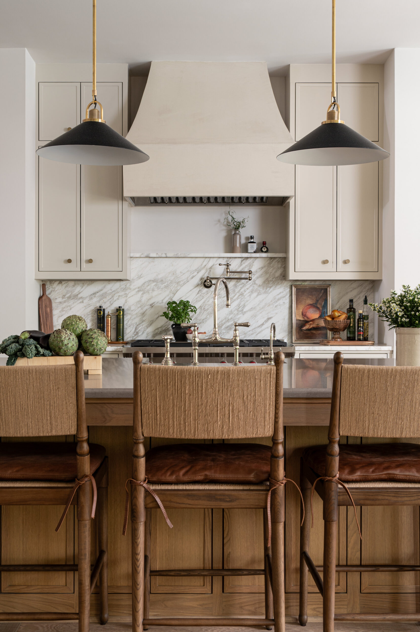 A modern kitchen with woven bar stools, leather seats, and natural wood tones, emphasizing texture in interior design by blending organic and refined materials throughout the space.

